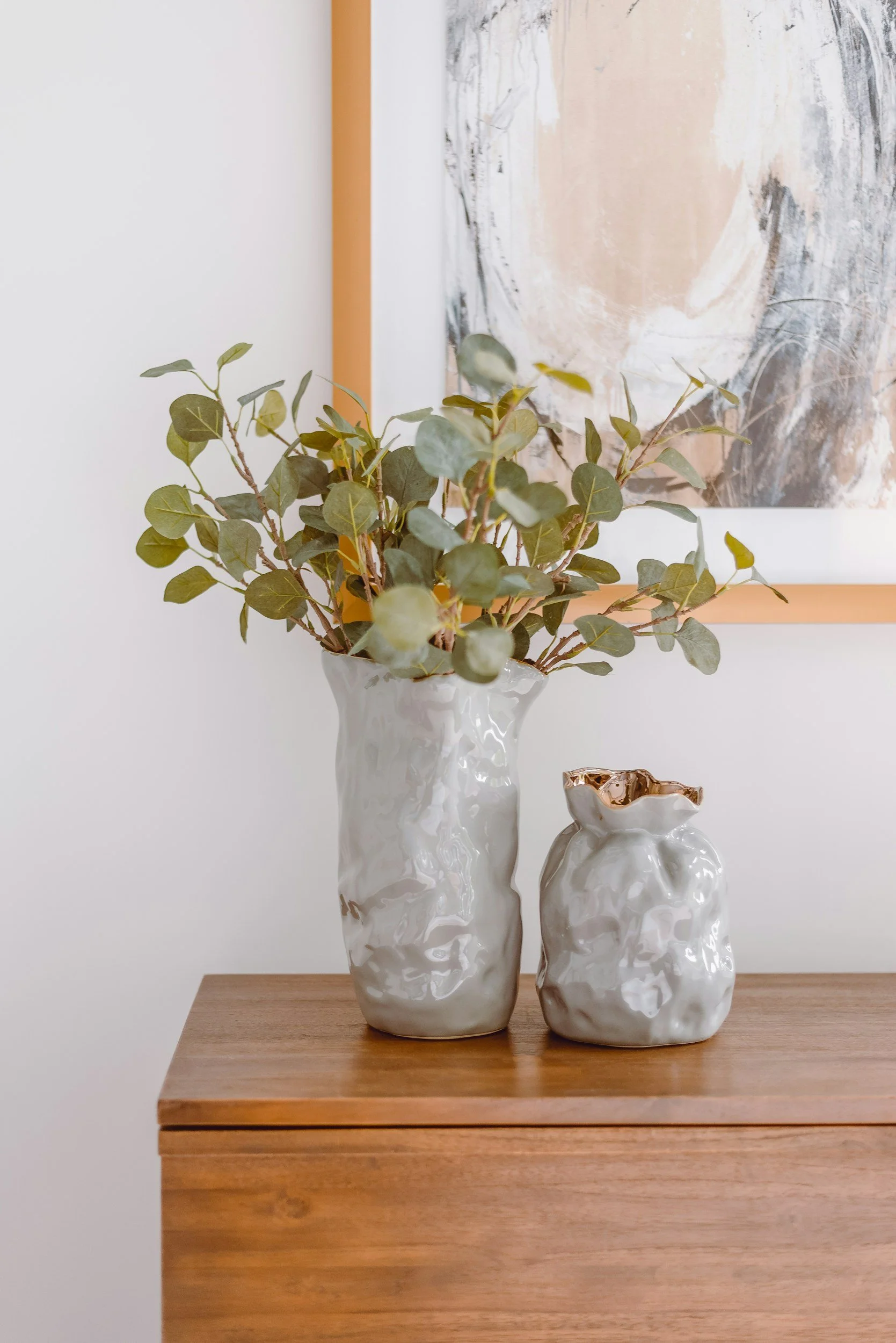 wood dresser with ceramic vases and eucalyptus