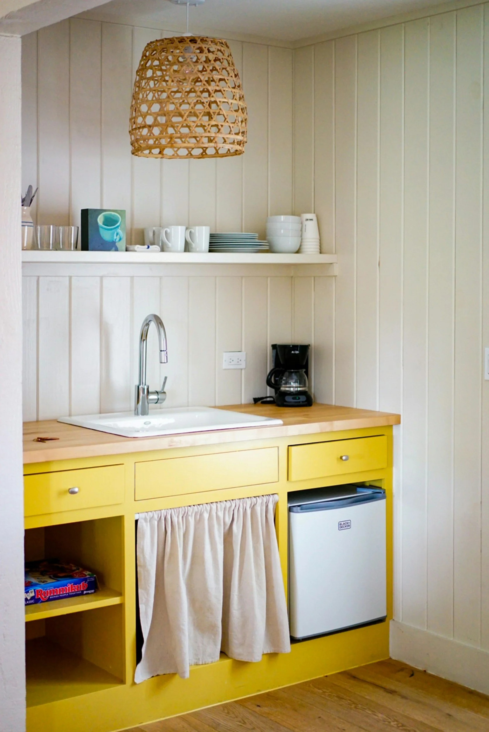 tiny kitchen with yellow cabinets and rattan pendant light