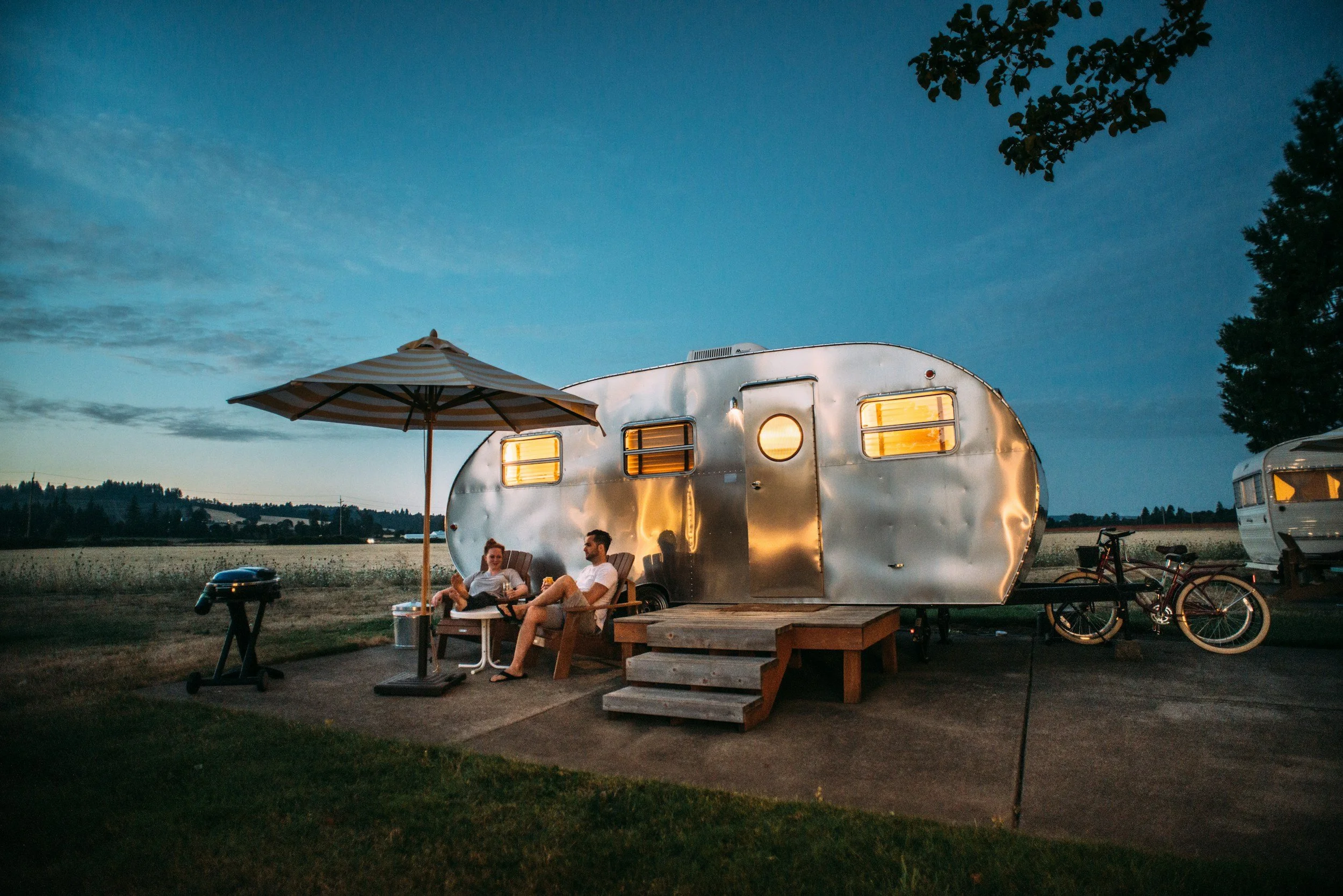 airstream trailer with umbrella lit up at dusk
