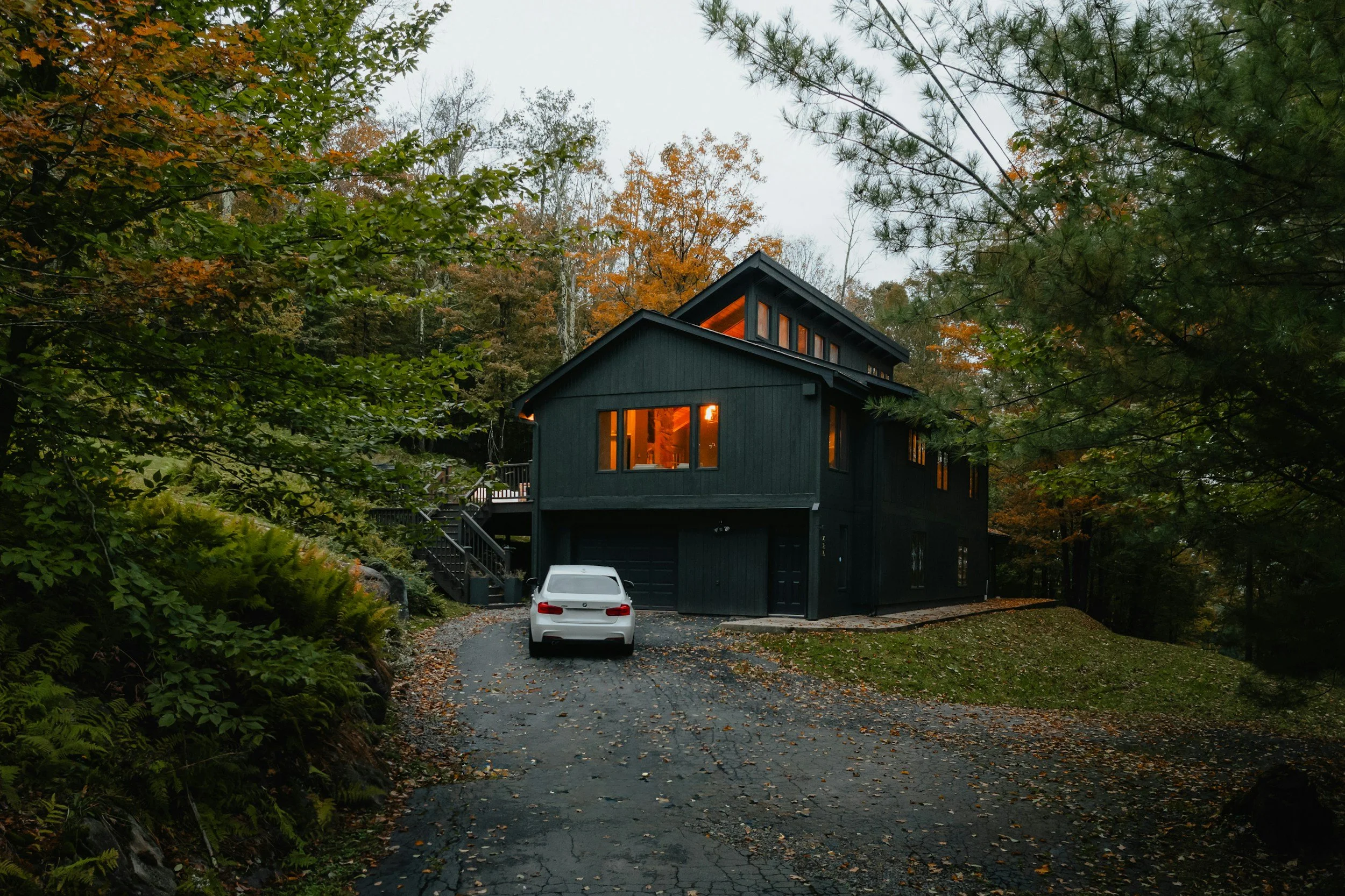black house with warm lit windows surrounded by trees
