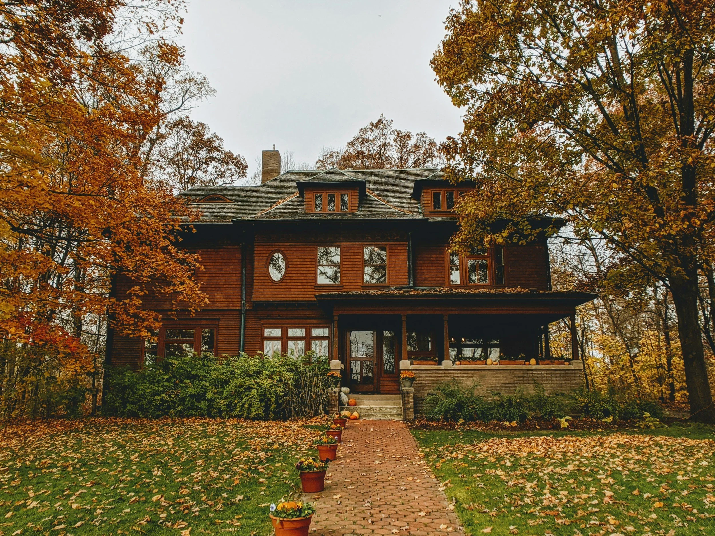 historic home with wood siding and fall leaves