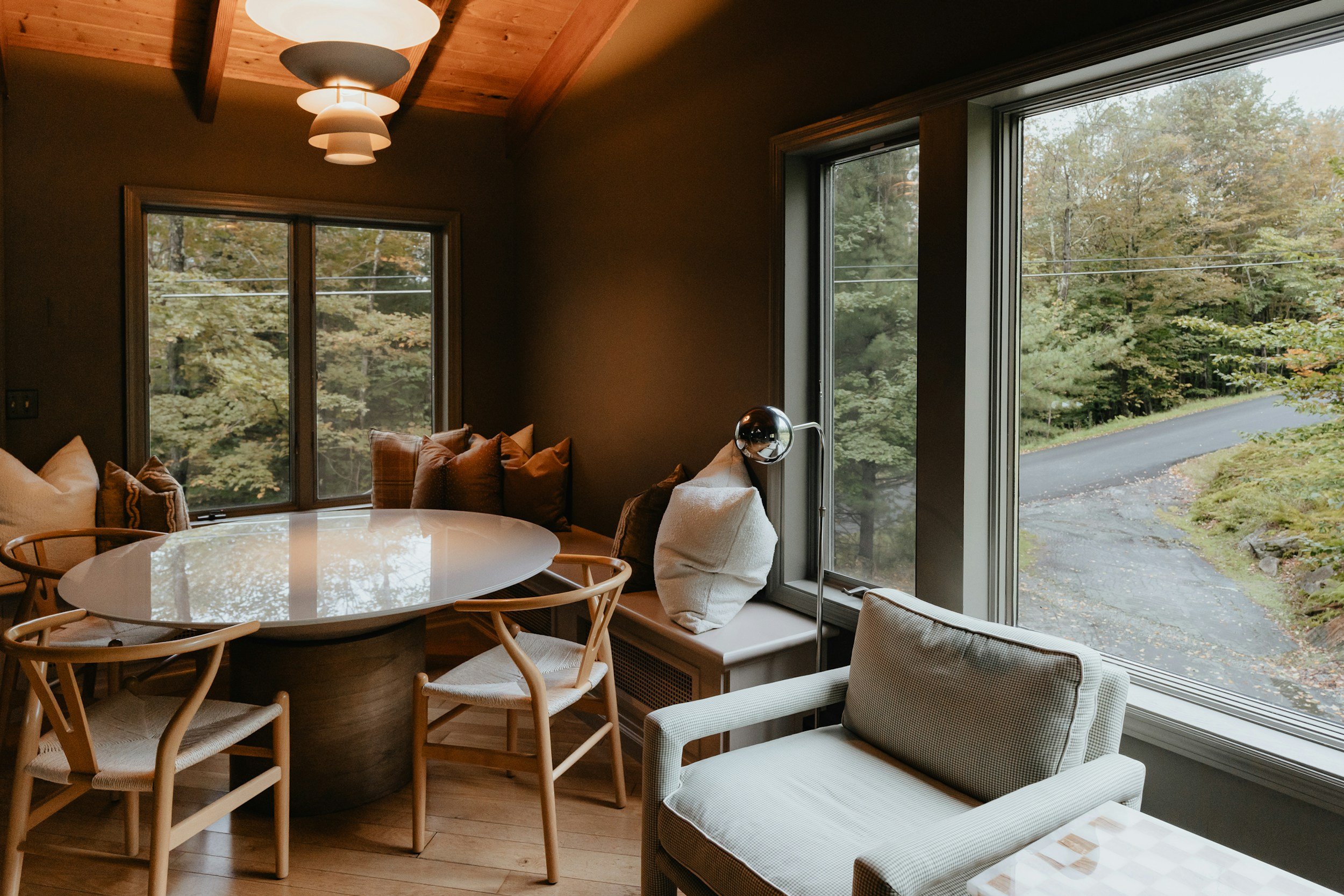 moody dining room with wood banquet and white armchair