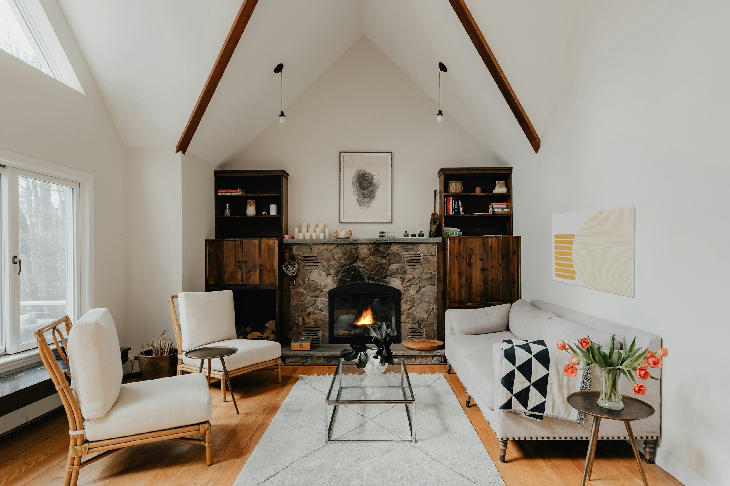 living room with white vaulted ceilings, wood beams, and stone fireplace