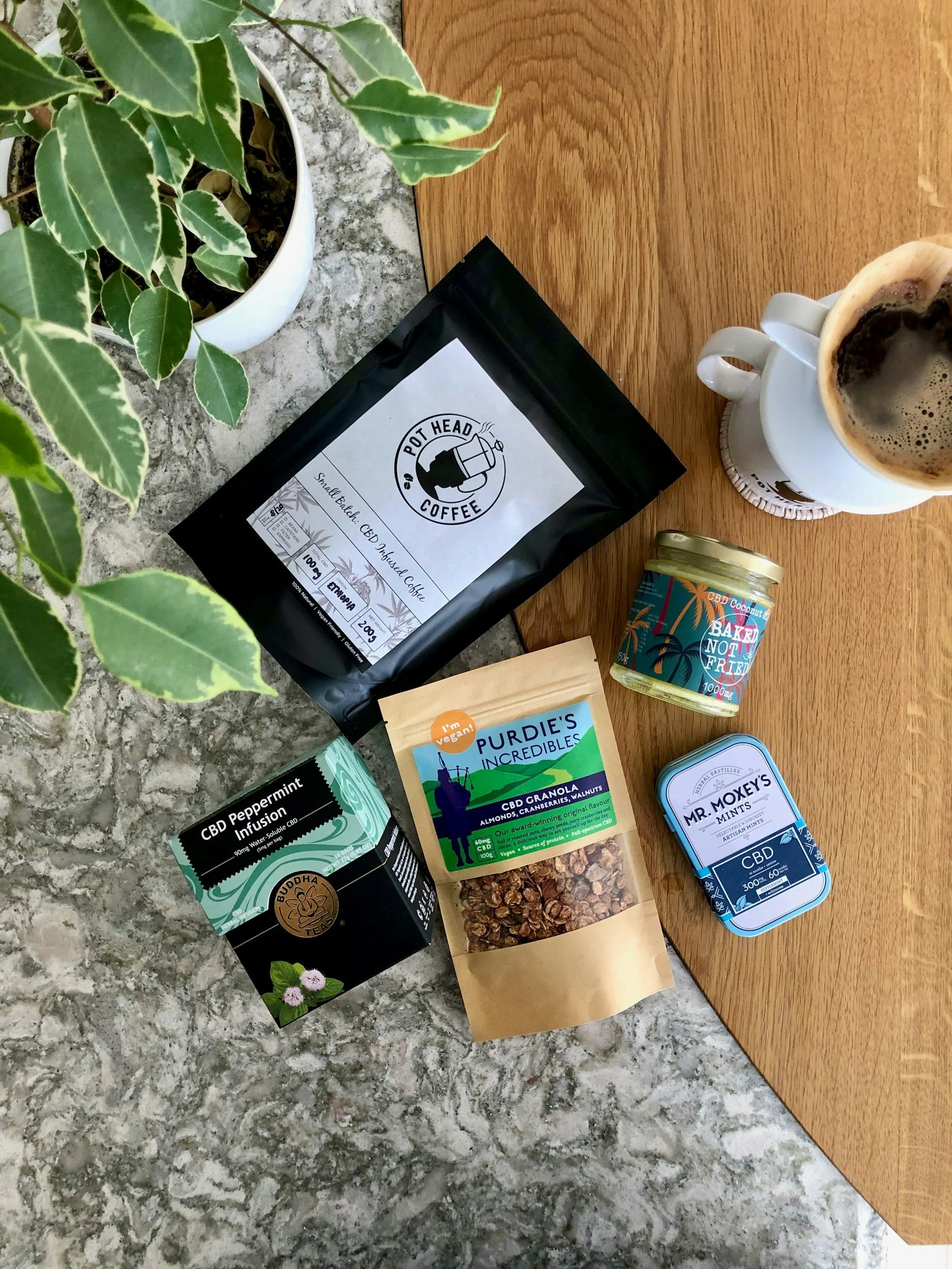 overhead view of plant with local coffee bag , granola, mints, and a up of hot coffee