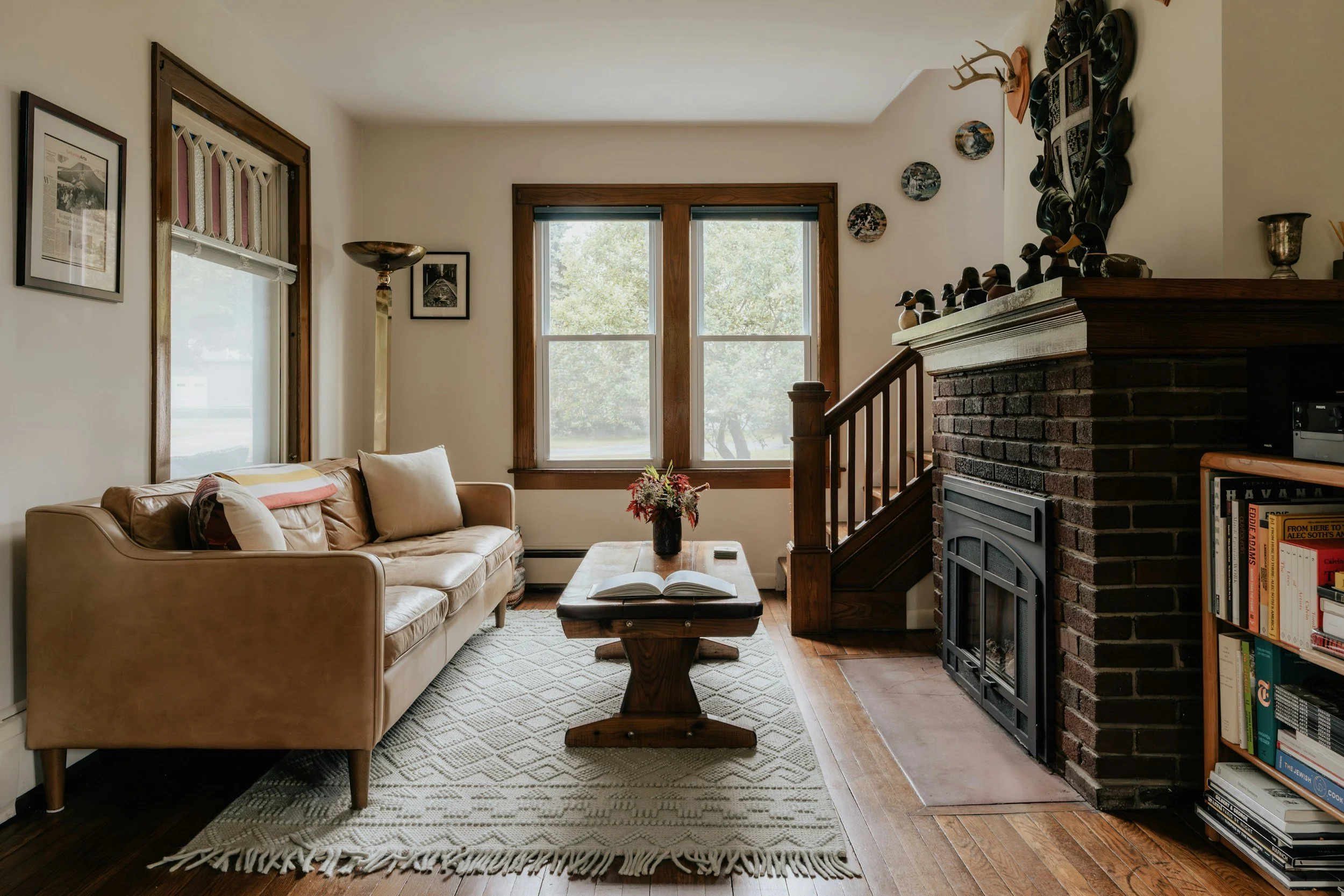 vintage brick fireplace with a tan leather sofa and wood floors