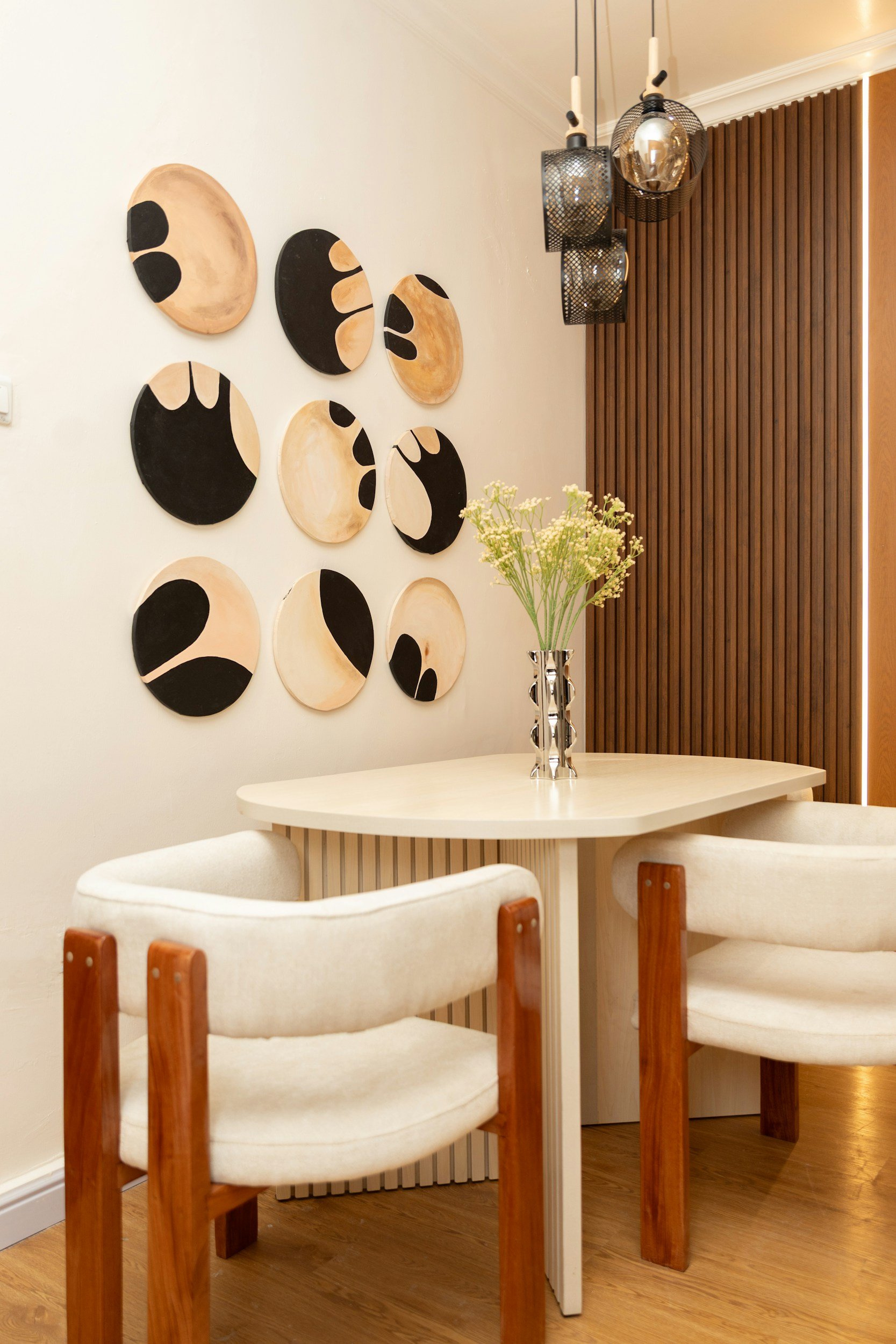black and white art behind a round dining table for 2 and a wood slat accent wall