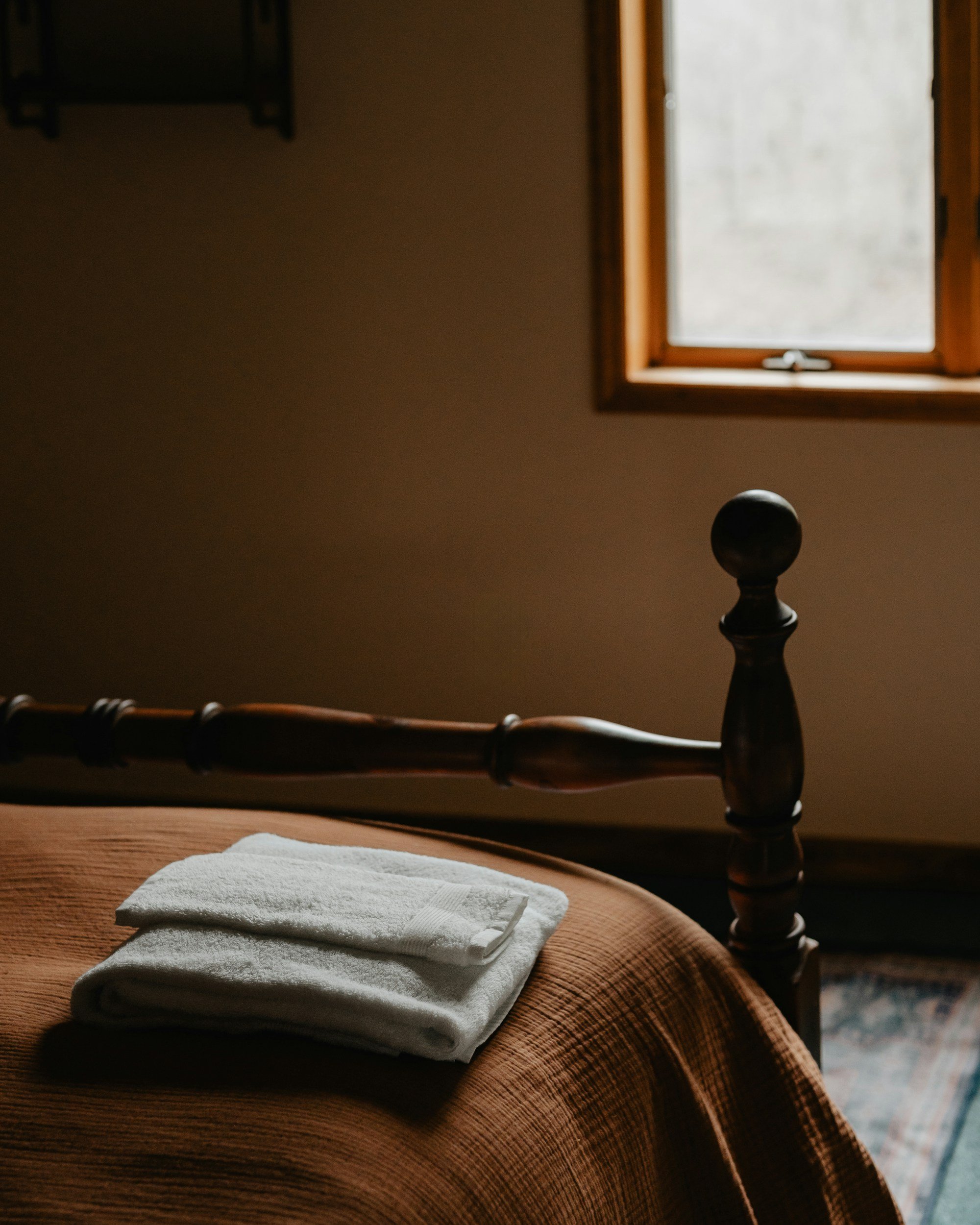 moody bedroom with orange muslin bedding and white towels