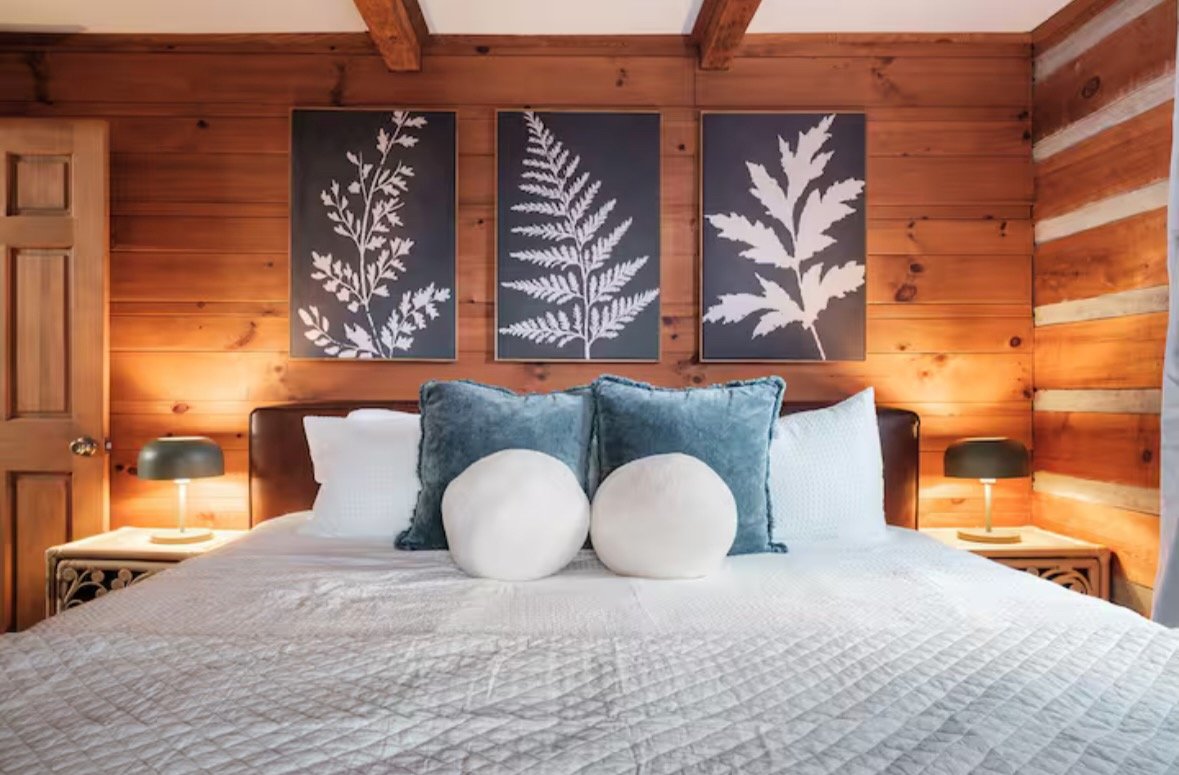 cabin bedroom with white bedding and framed branch art