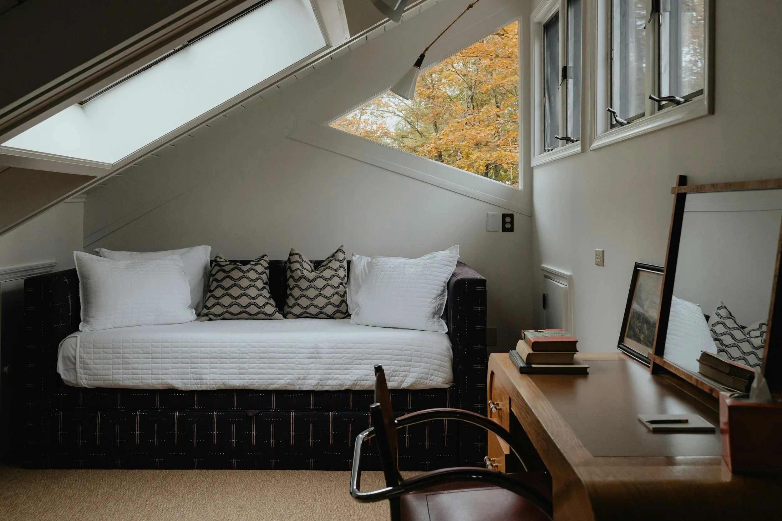 vintage loveseat and desk infront of a triangular window