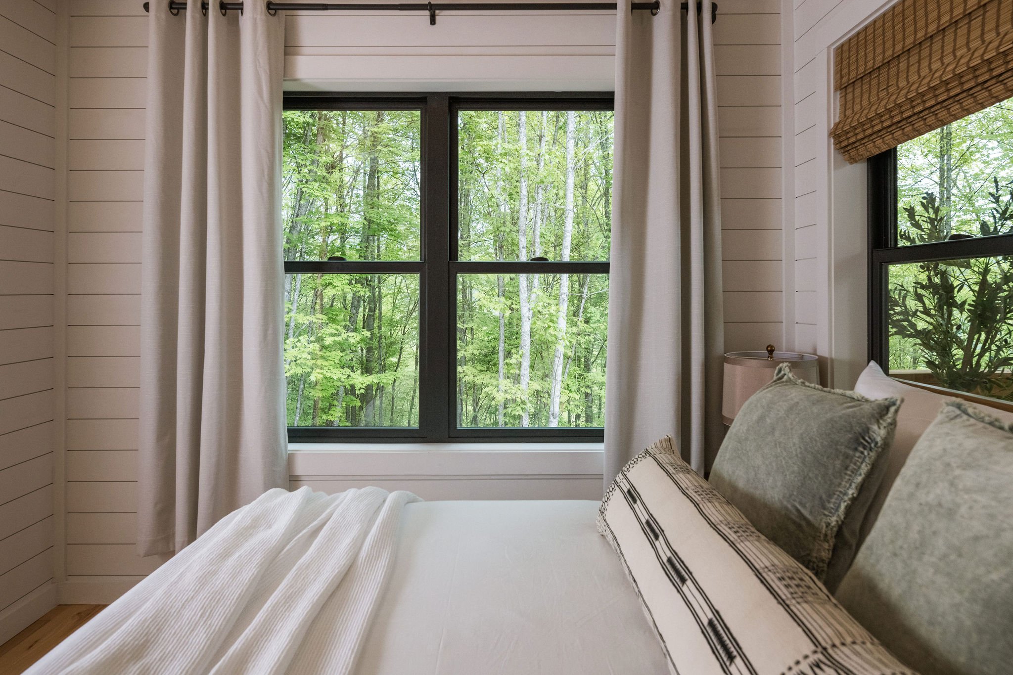 white shiplap walls with green throw pillows and a black and white lumbar pillow