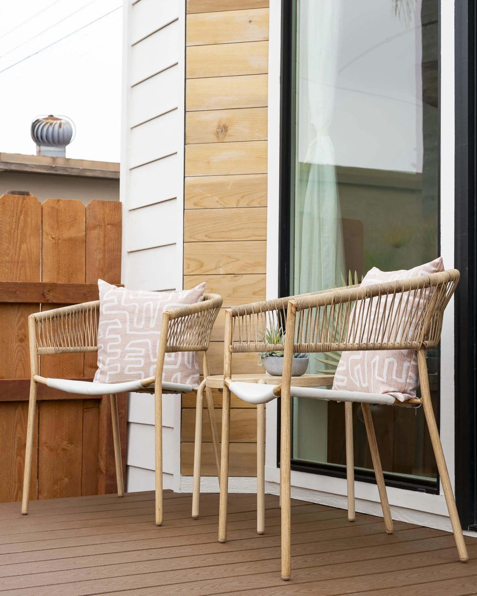 patio with rattan chairs and pink throw pillows