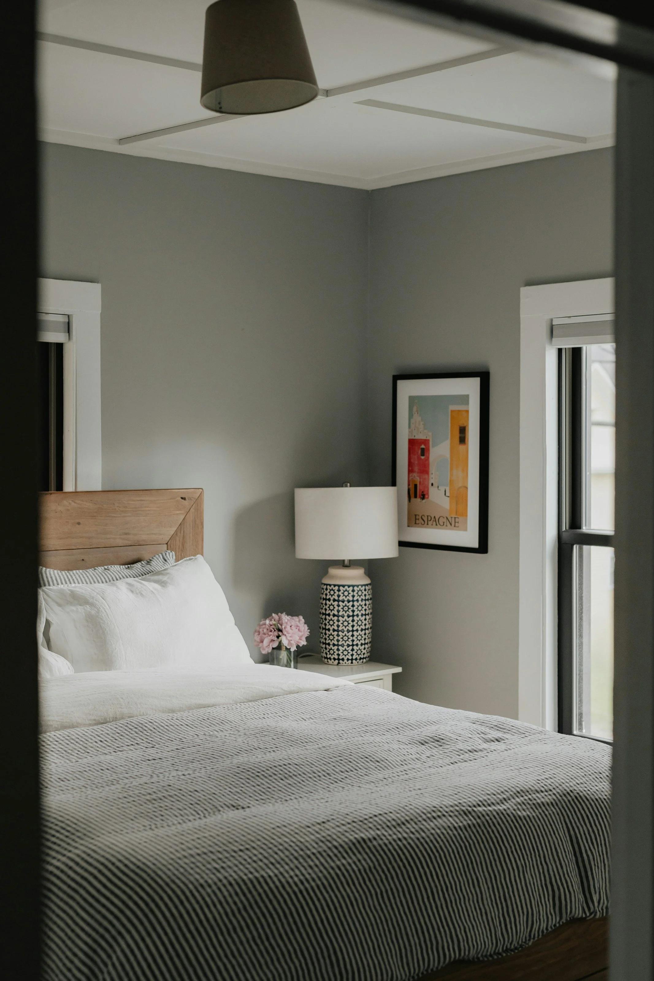 small bedroom with stripped bedding and geometric print lamp