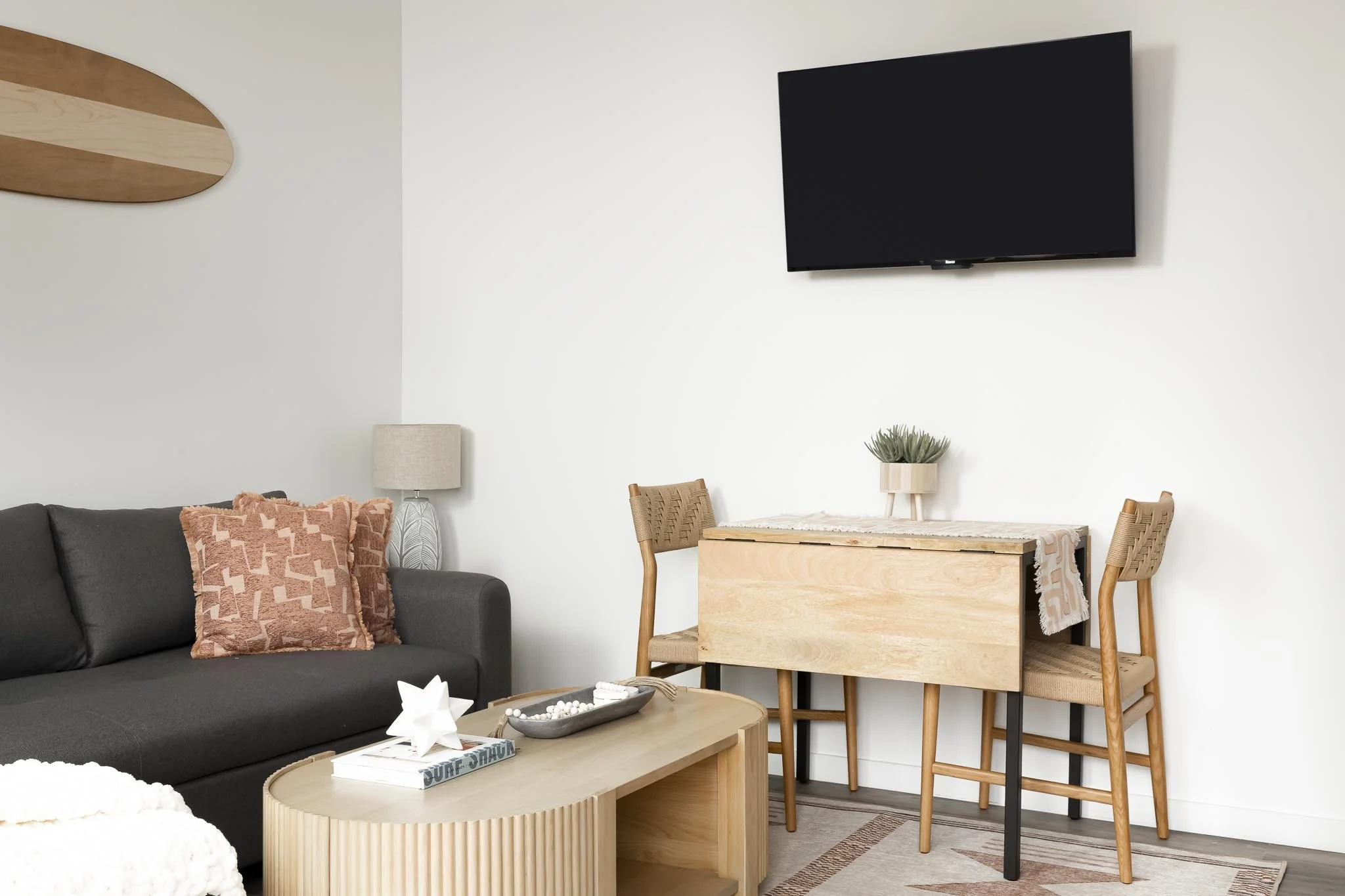 minimal light filled tiny home living room with folding dining table and pink throw pillows