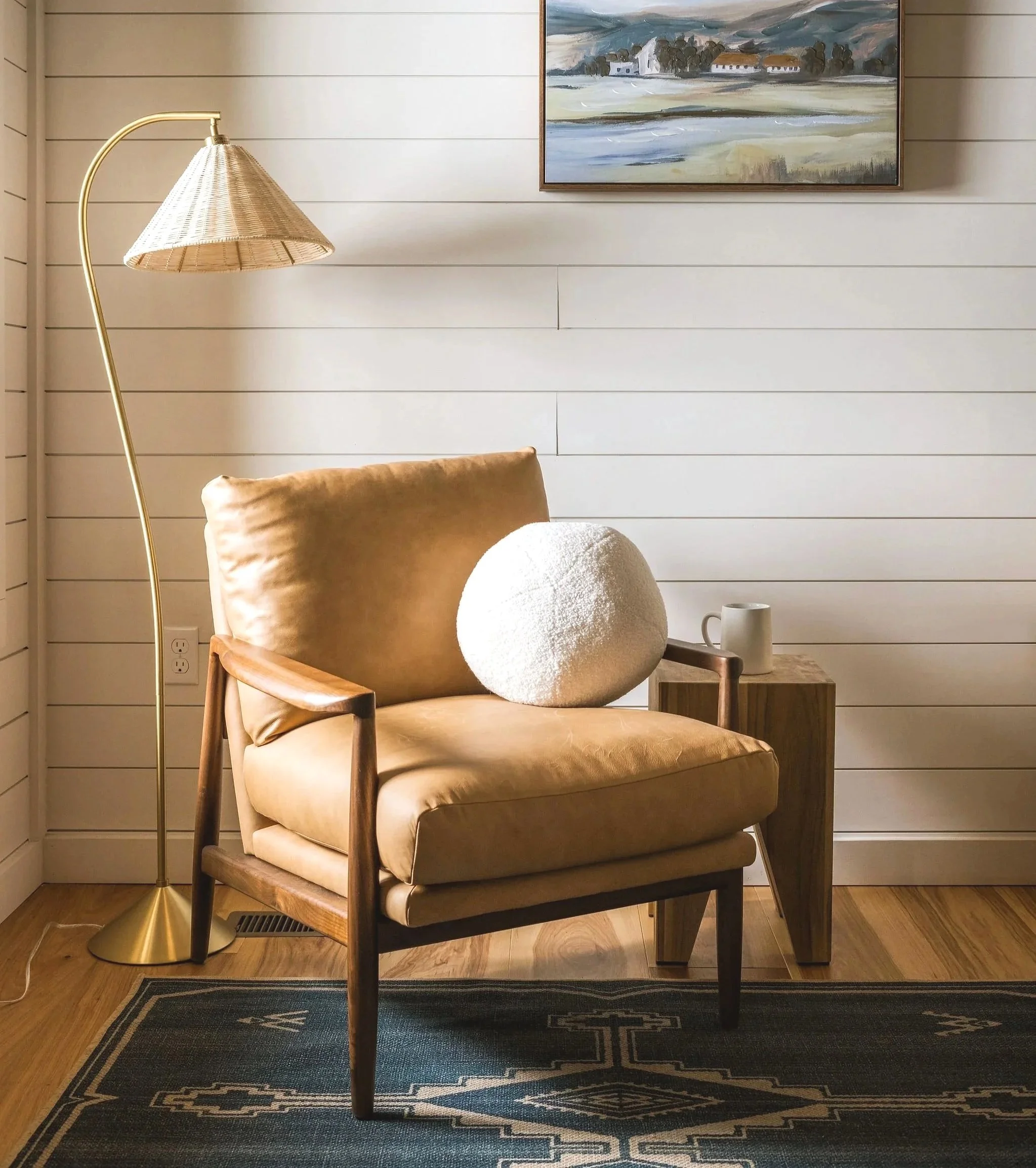 leather armchair with shiplap walls and a woven floor lamp
