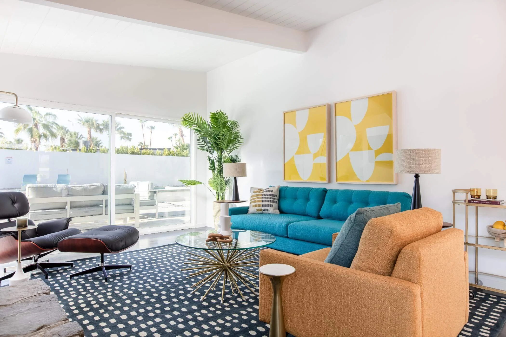 turquoise sofa with orange armchair and black and white rug