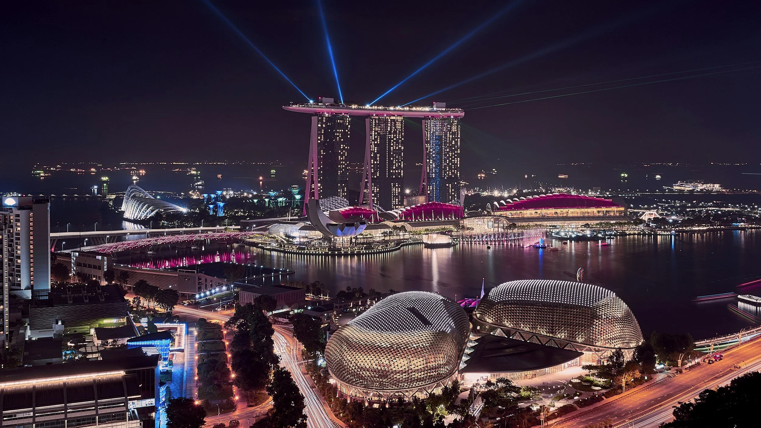 Night view of Singapore skyline with Marina Bay Sands hotel and artscience museum illuminated with colorful lights.