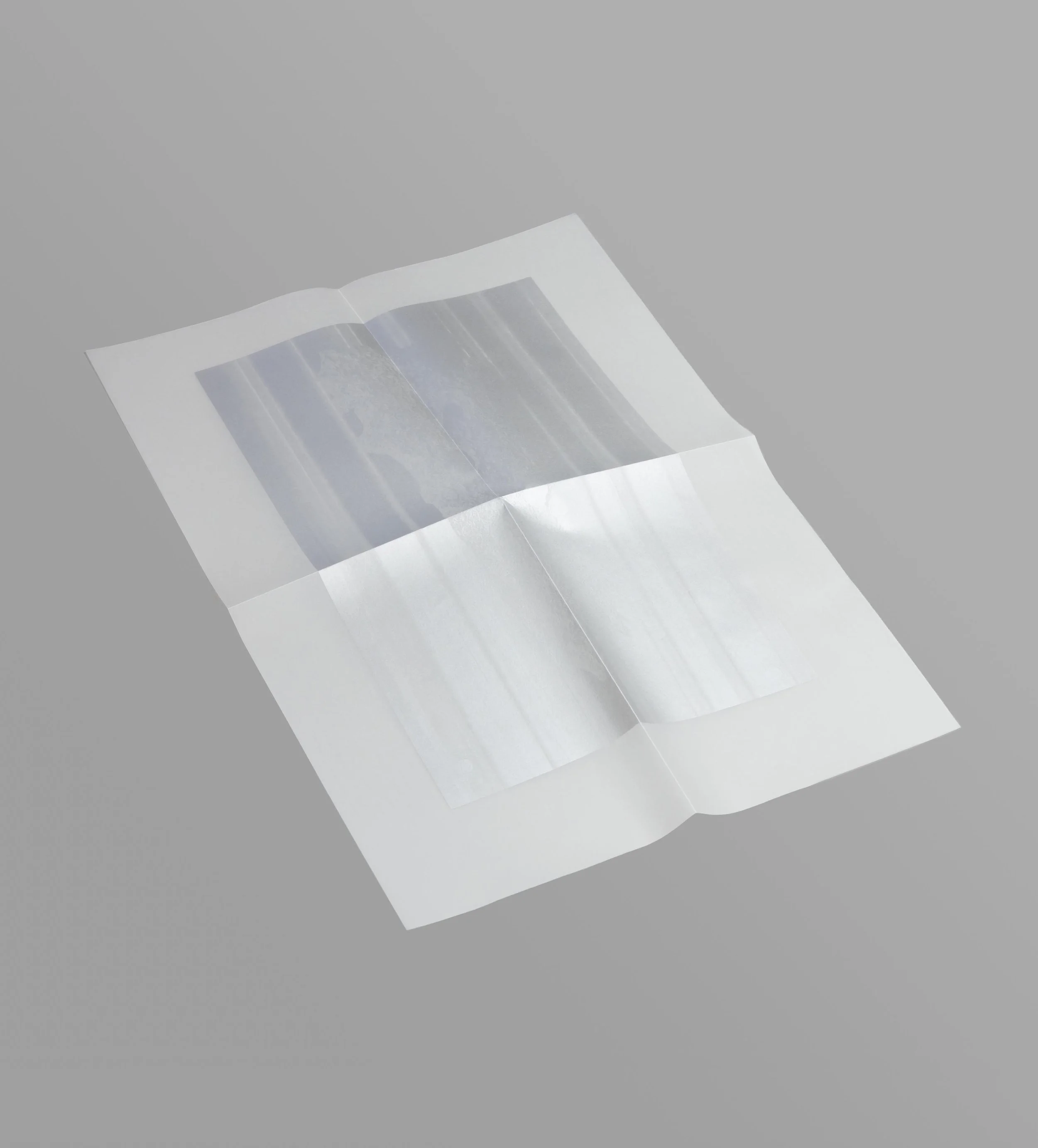 An open book with transparent pages lying on a gray surface.