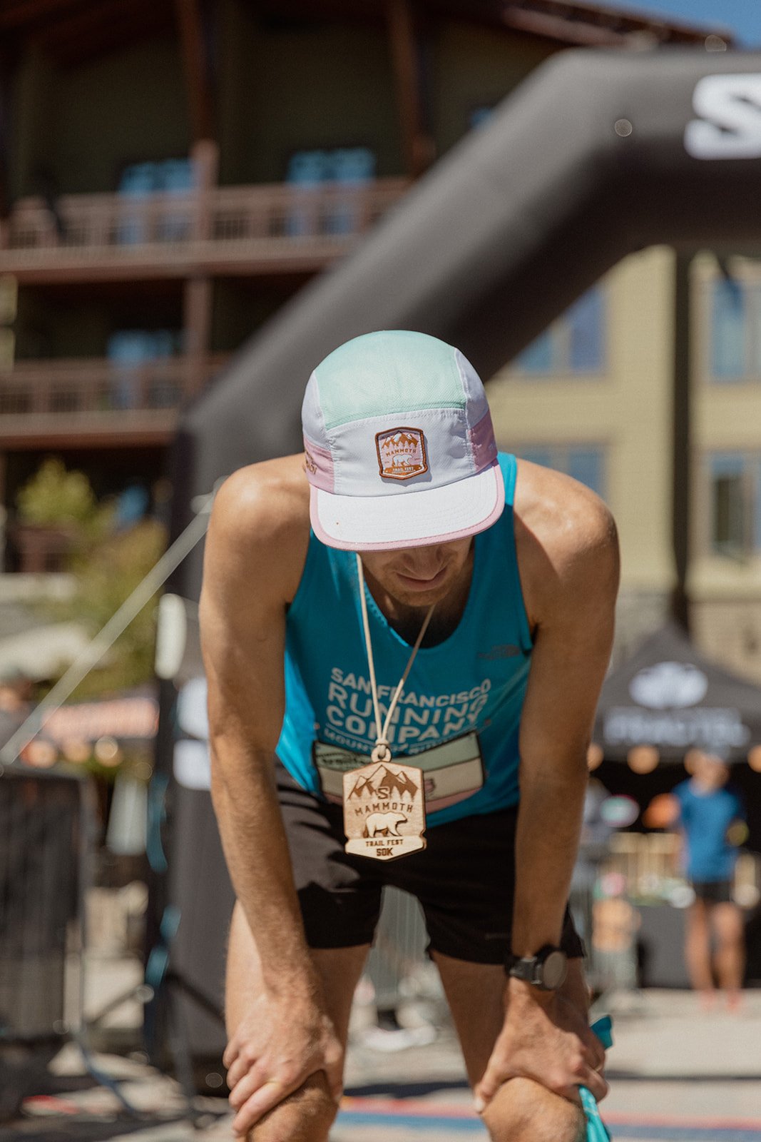 A male runner, bent over at the finish line of mammoth trail fest looking exhausted