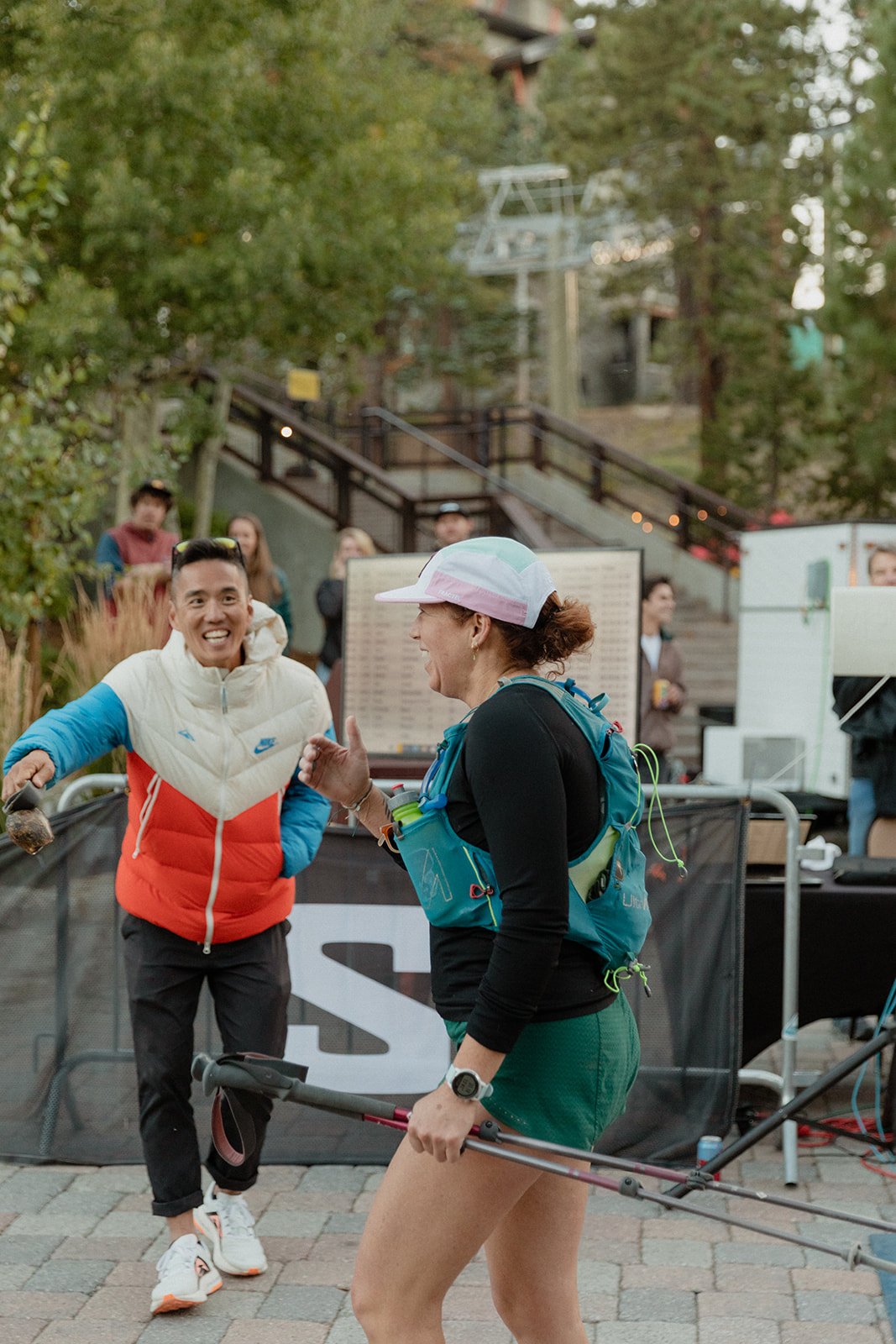 A female runner smiling as she finishes mammoth trail fest, billy yang handing out medals