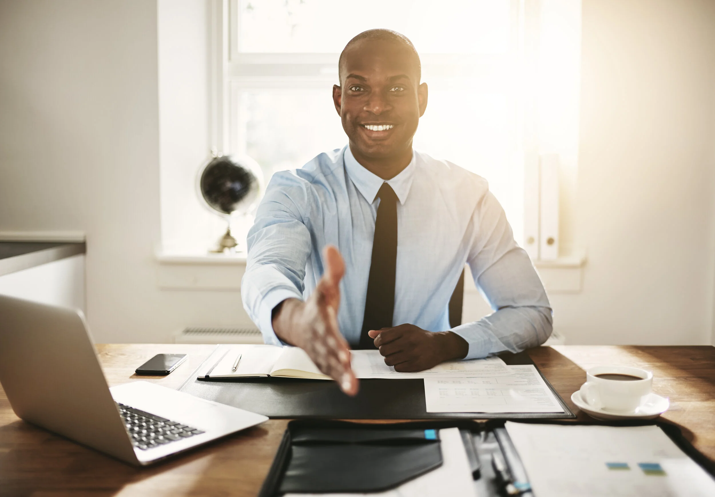smiling-young-executive-sitting-at-his-desk-extend-MPS2VXK.jpg