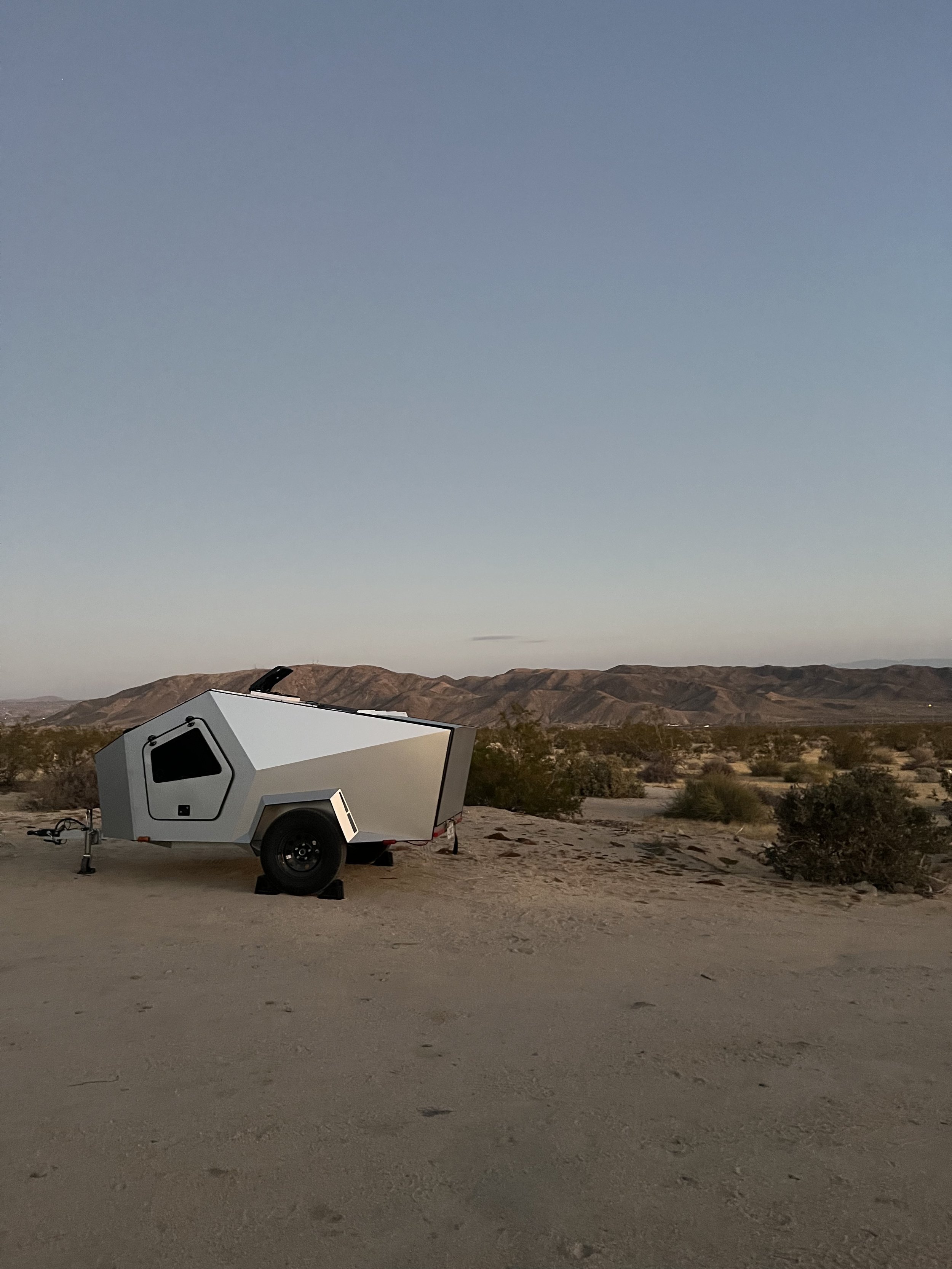 Minimal trailer in desert landscape under wide sky.
