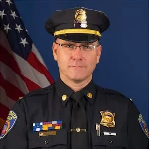 Portrait of a police officer in uniform with American flag in the background.