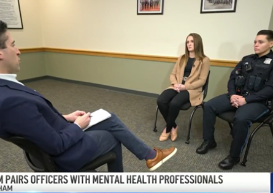 A man and a woman sit in chairs during a discussion with a mental health professional.