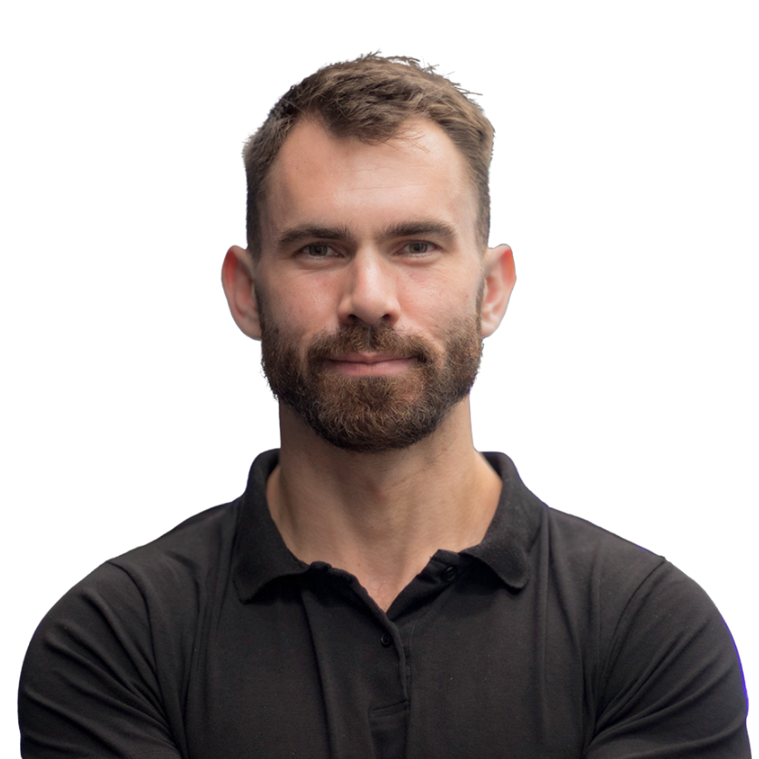 Portrait of a young man with short brown hair, a full beard, wearing a black polo shirt, looking directly at the camera with a slight smile.