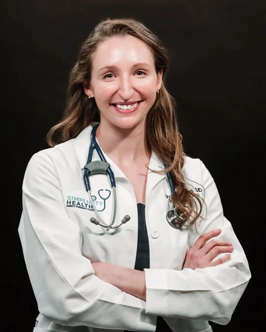 A smiling Dr. Marton, a female doctor professional wearing a white lab coat with a stethoscope around her neck, standing against a black background.