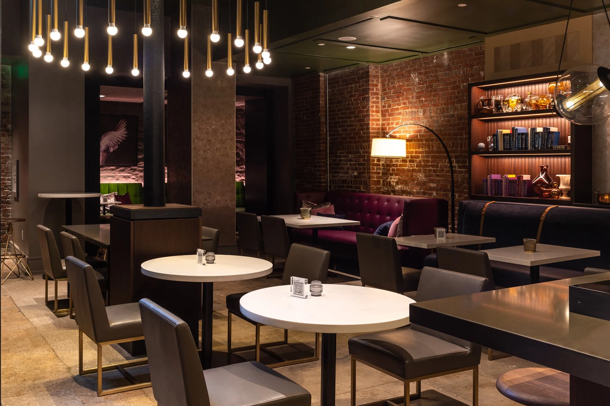 Interior of a modern restaurant with tables, chairs, exposed brick walls, and decorative lighting.