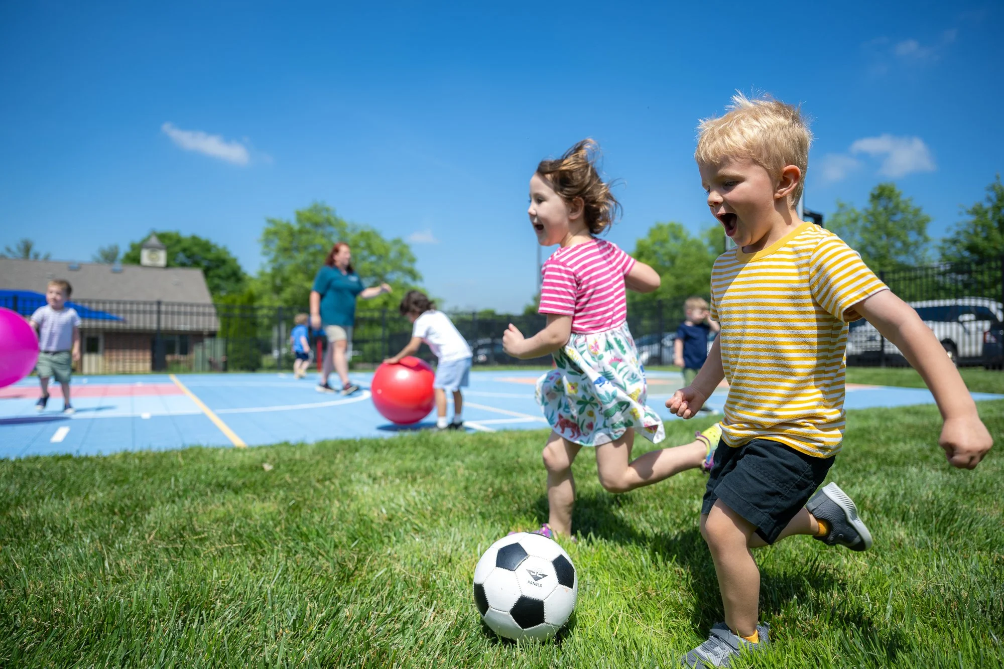 Children playing soccer and enjoying outdoor activities on a sunny day at a park or playground.