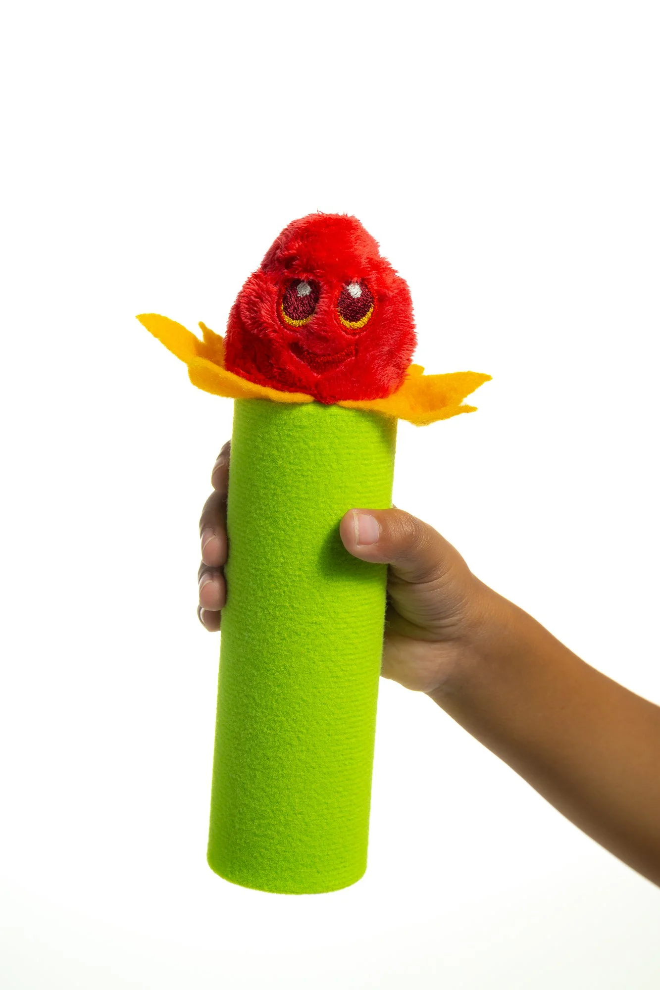 A hand holding a sock puppet resembling a red berry with a smiling face, yellow felt leaves, and a green sock body, on a white background.