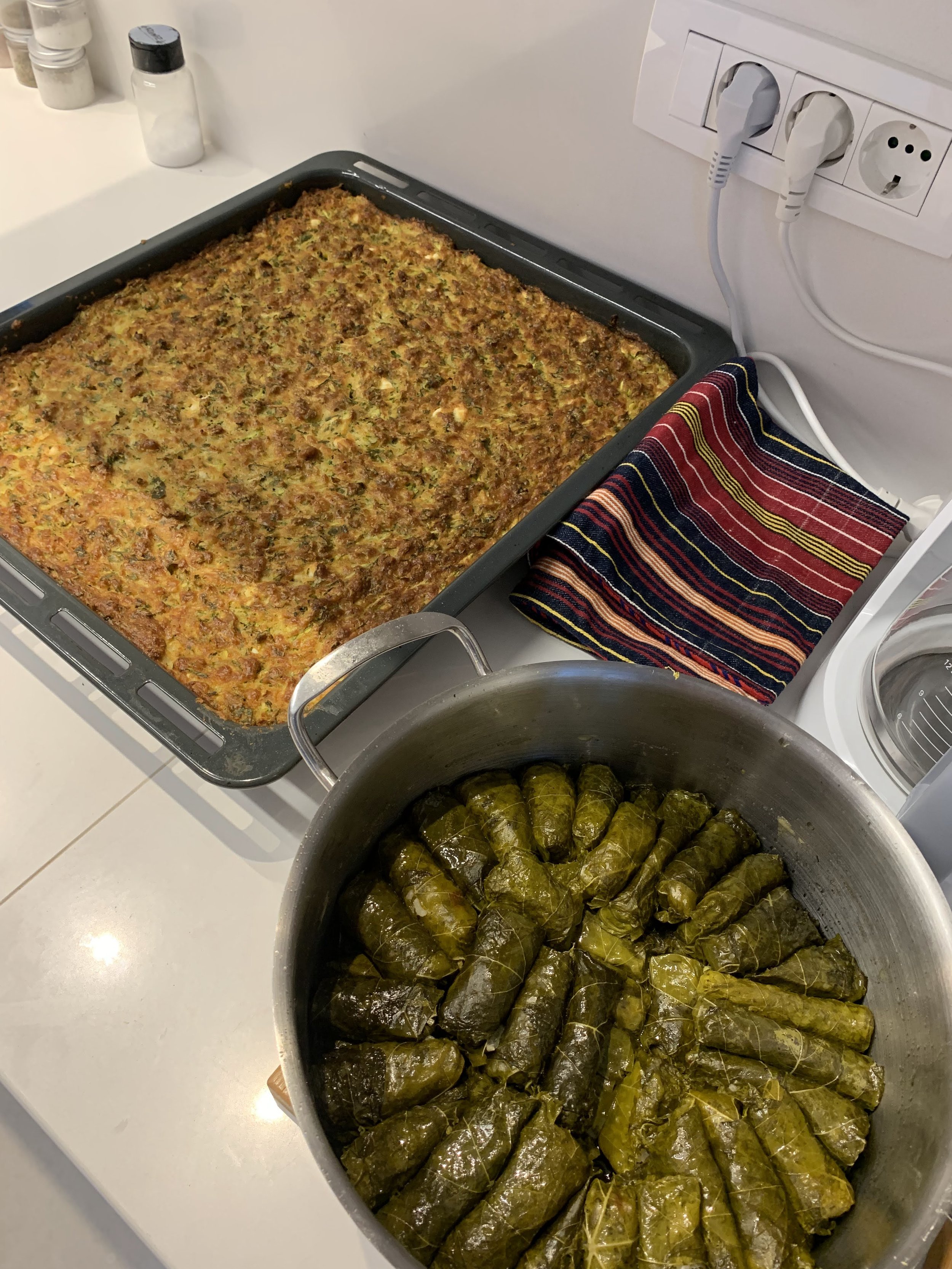 Baked zucchini casserole and stuffed grape leaves in a kitchen setting.