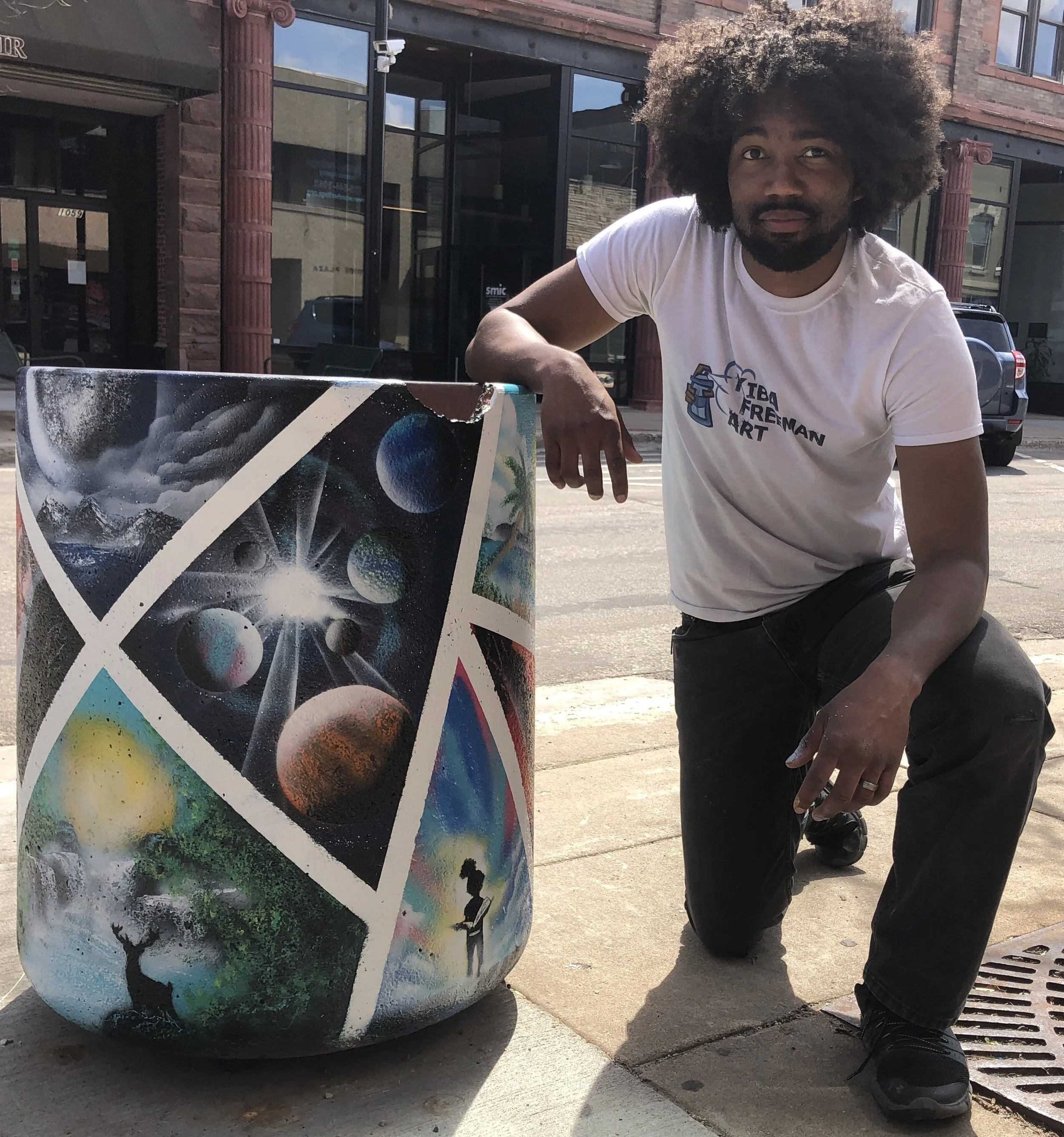 Kiba kneels next to finished work with space and natural scenes.