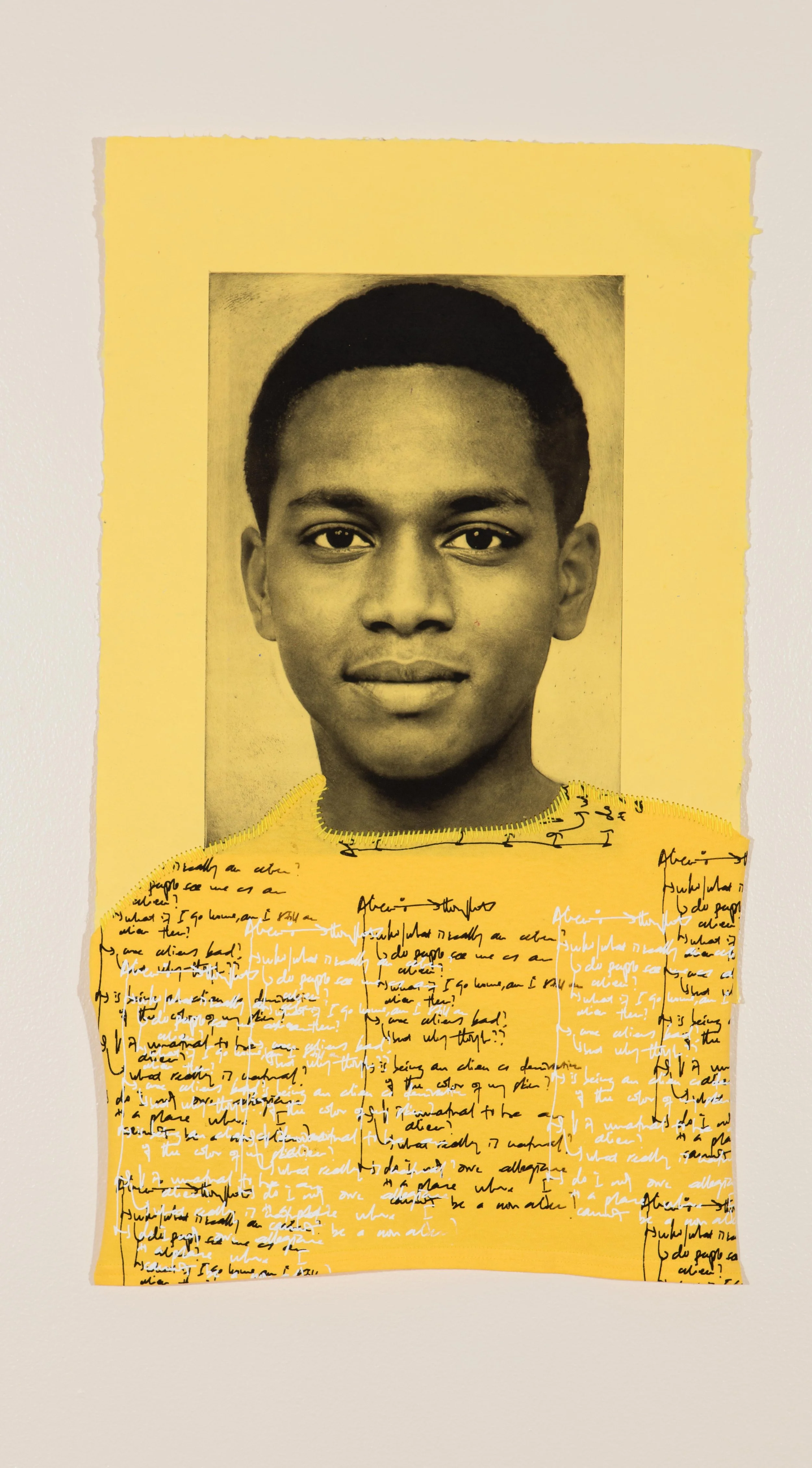 Portrait of young Black man on yellow paper, with white and black handwriting on his shirt.