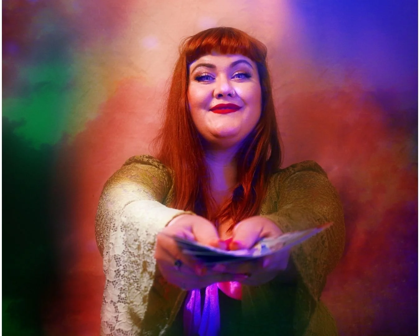 DeAnnah is holding out a fanned deck of tarot cards, inviting the view to pull one