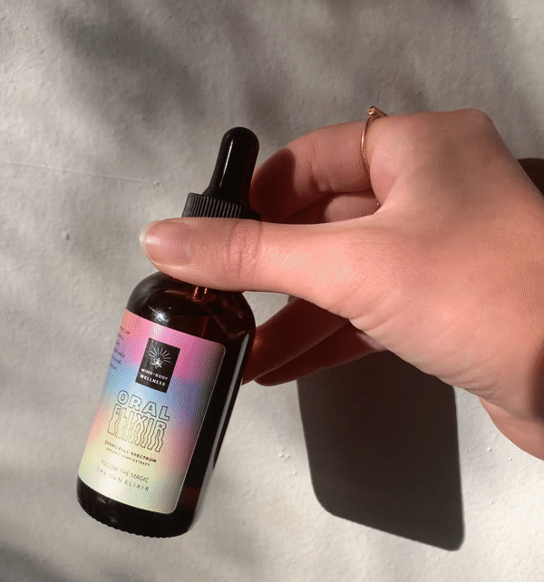 Hand holding a bottle labeled "Oral Elixir" with a dropper cap.