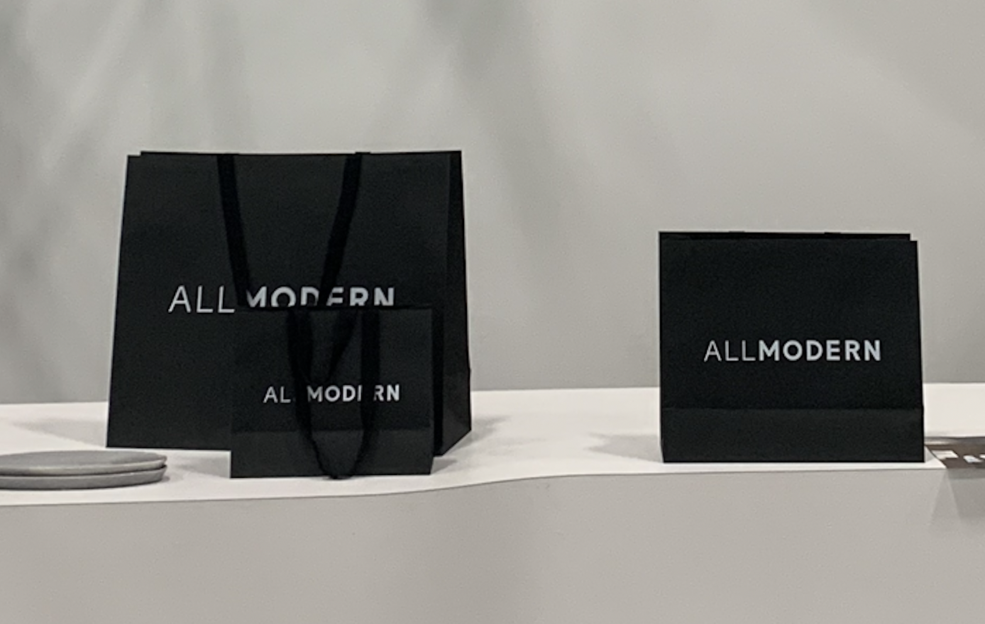 Black shopping bags with 'ALLMODERN' logo on a white surface.