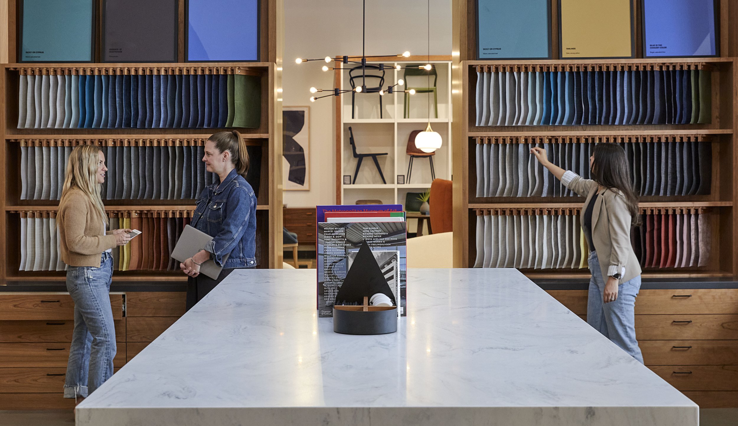 Three women in a showroom with fabric samples on display