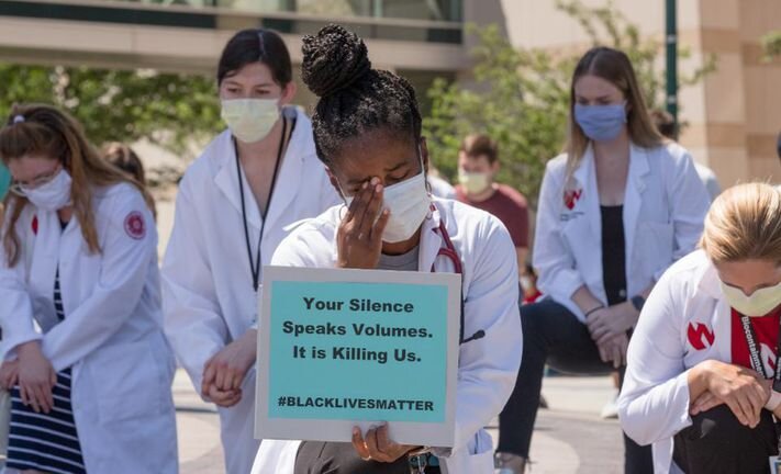 Jasmine Marcelin MD, wipes away a tear during a #WhiteCoatsForBlackLives rally at the University of Nebraska Medical Center where she works as an infectious disease physician.  UNMC/NEBRASKA MEDICINE/KENT SIEVERS