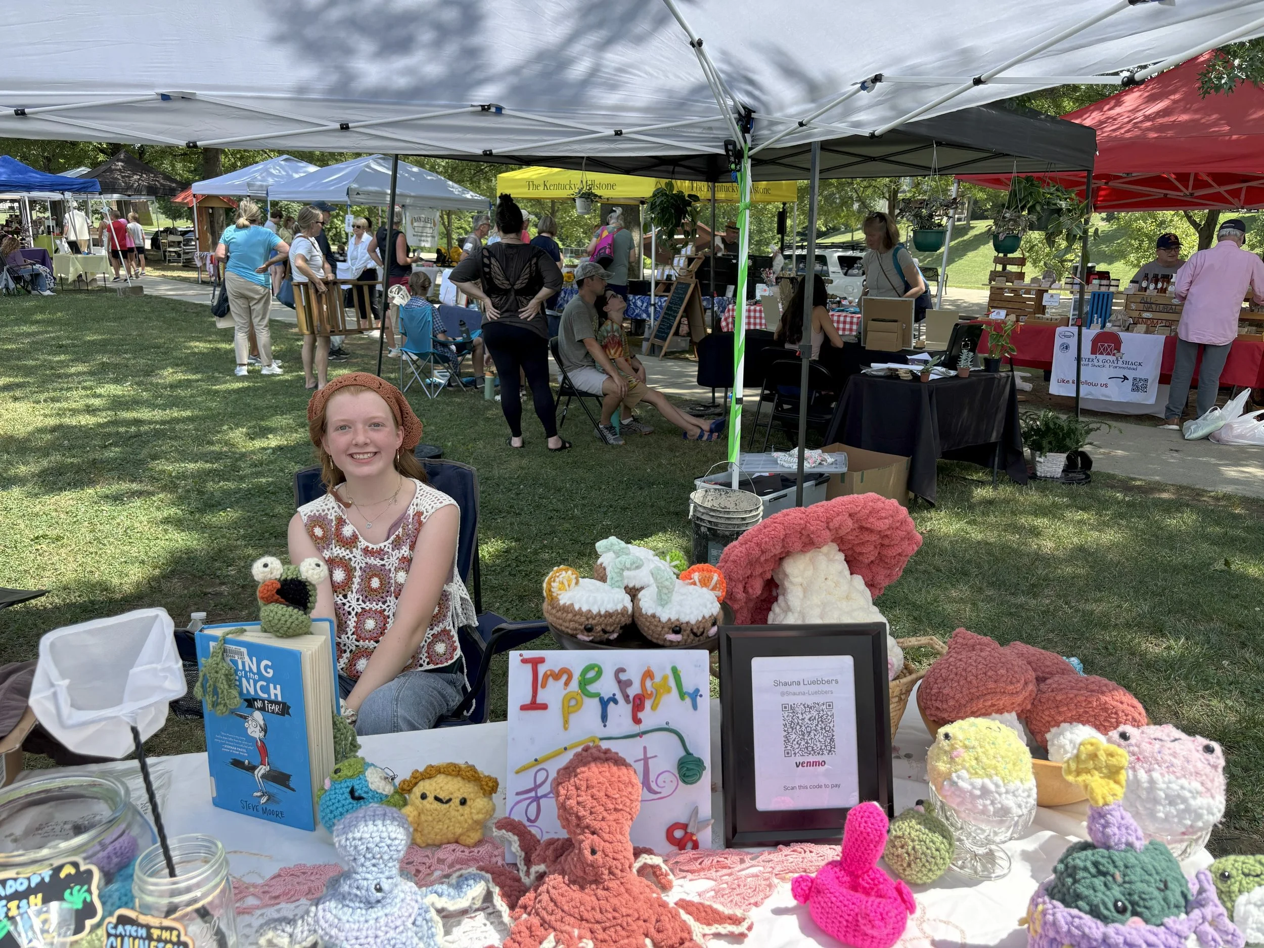 Girl sitting under a tent with crocheted animals