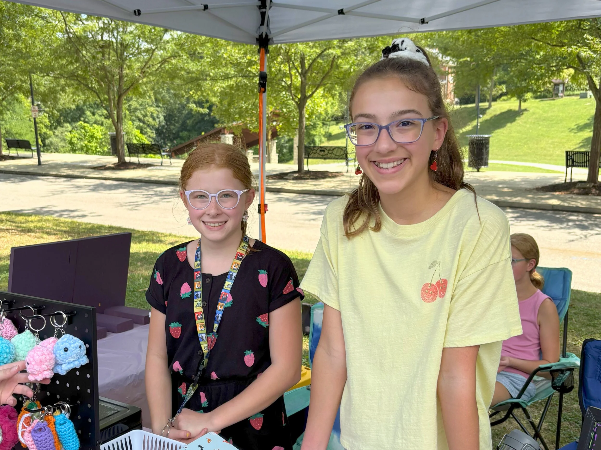two girls smiling under a market tent