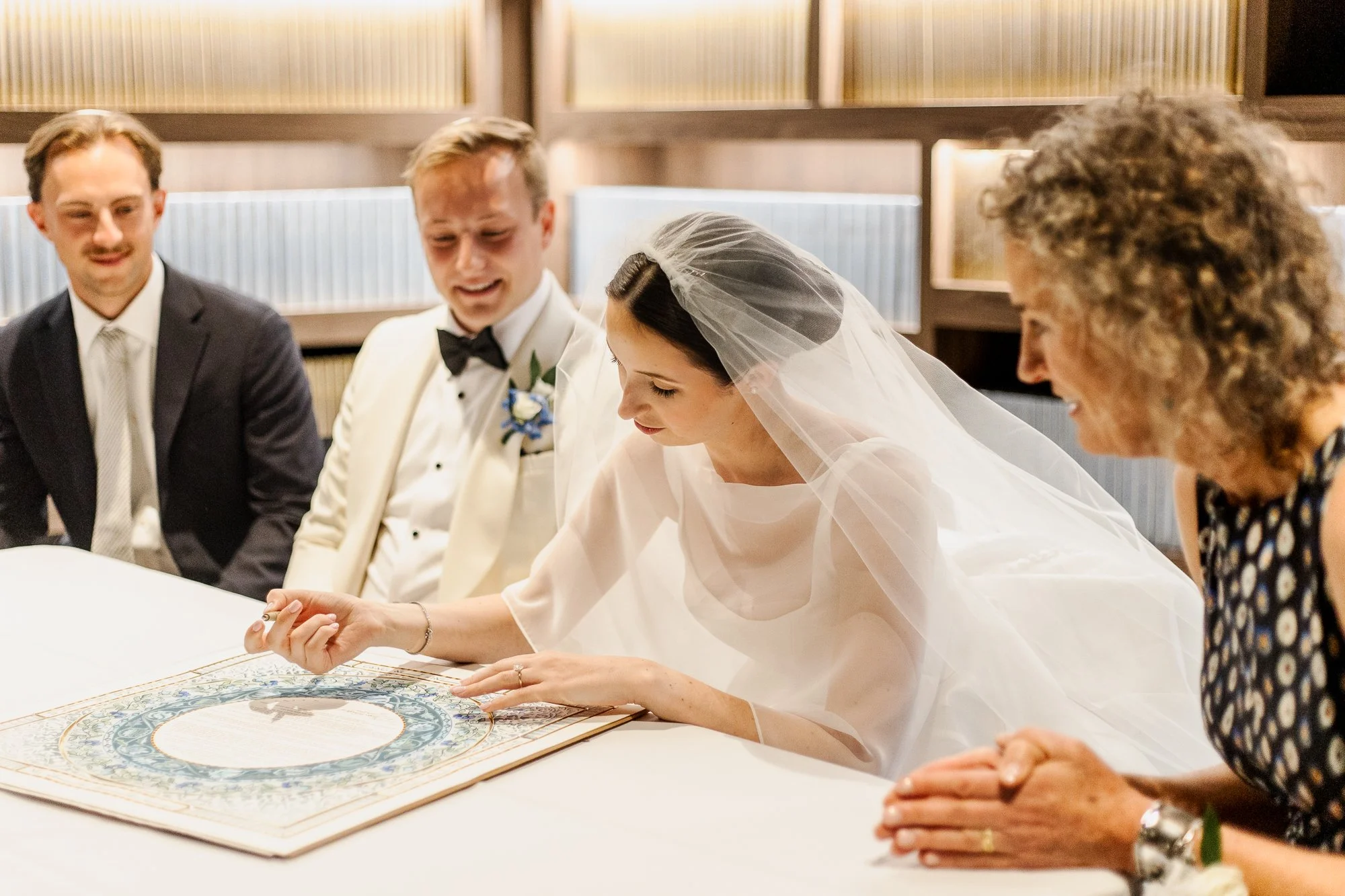 Sarah and Owen signing their ketubah in front of family and friends