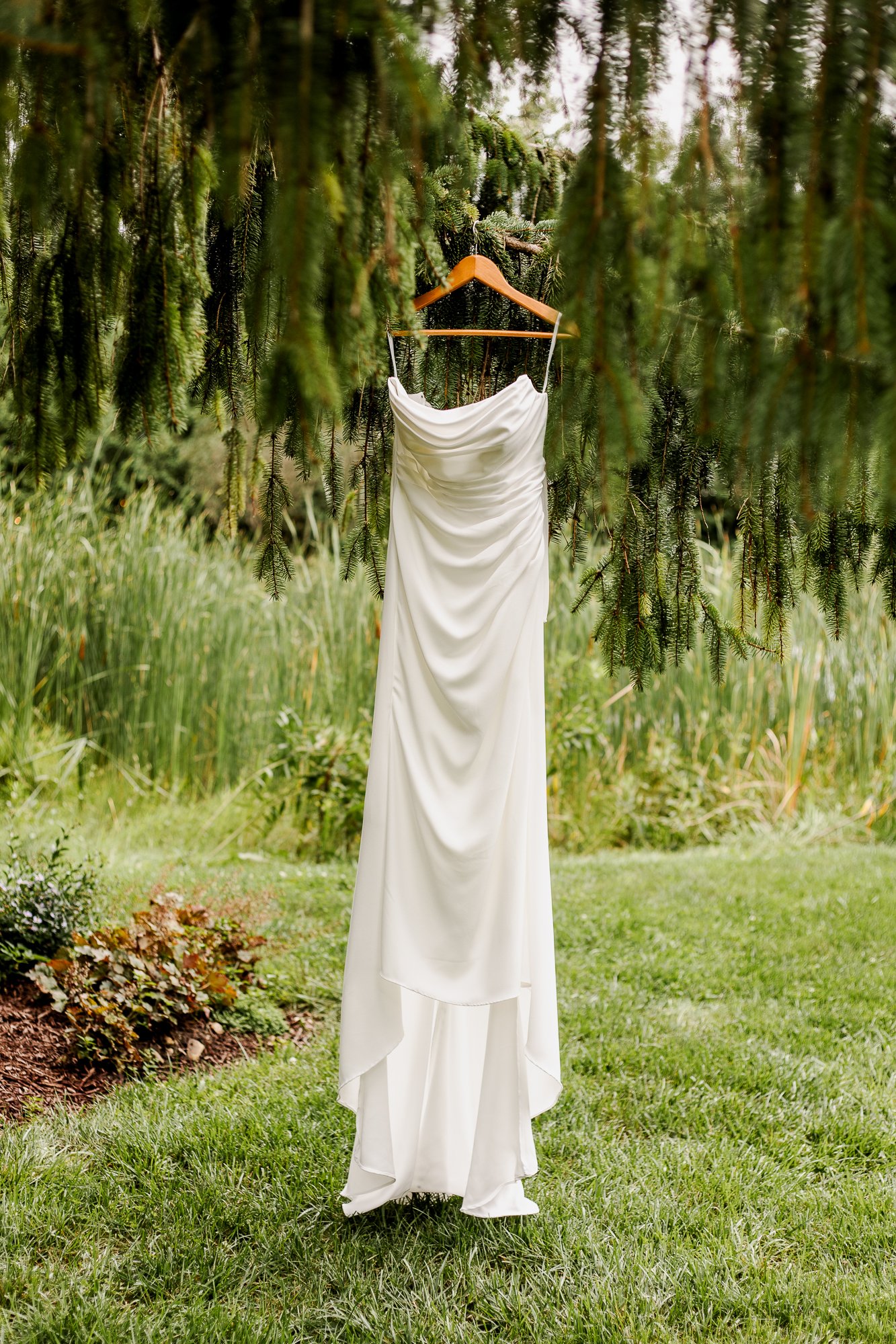 sleeveless wedding dress hanging in a pine tree