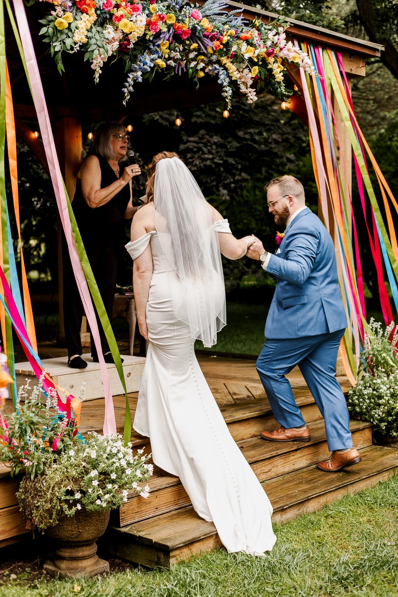 Full lenth shot of groom helping bride up stairs of gazebo at bloom and bower in rising sun ohio
