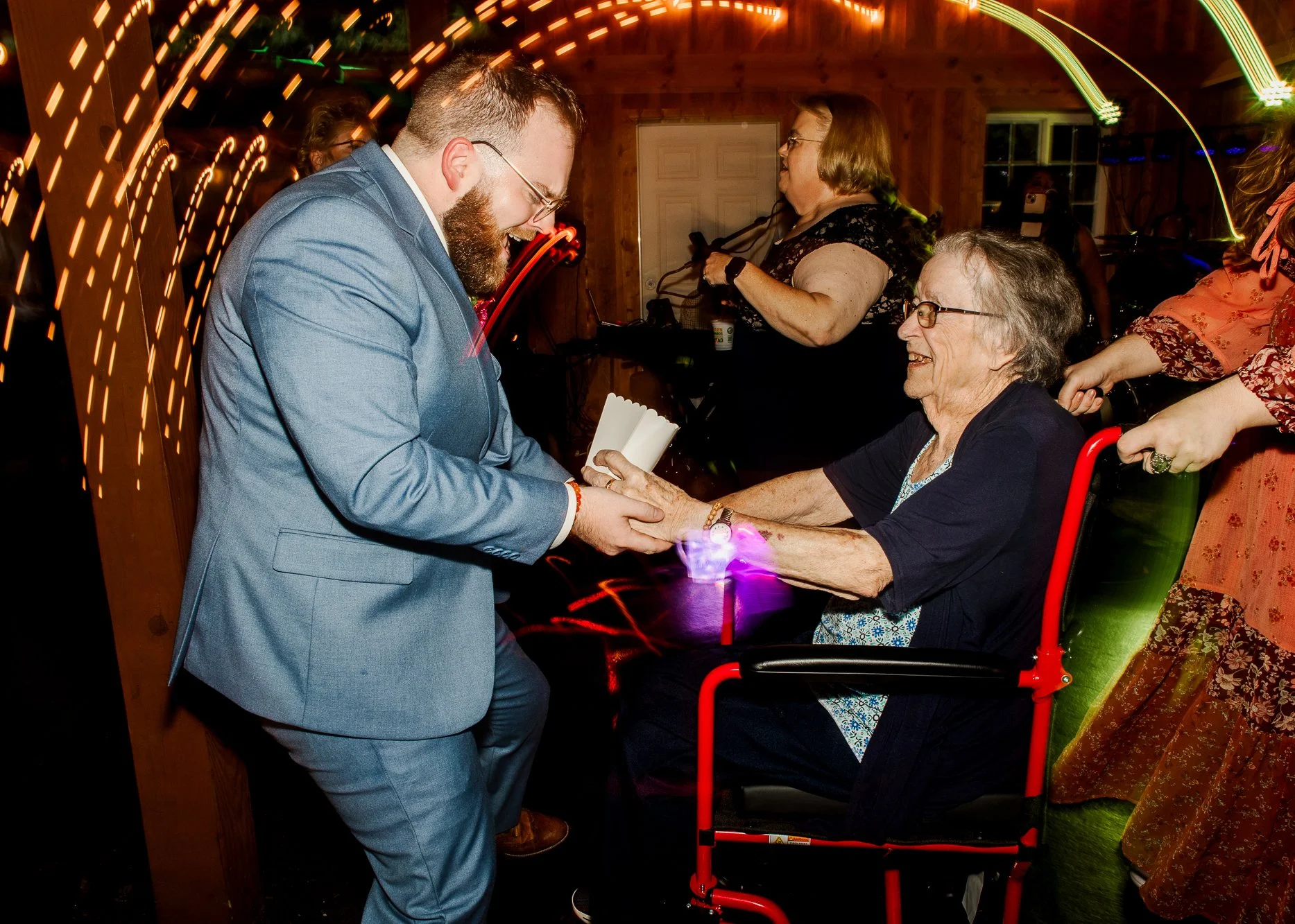 groom and wedding guest dancing together on a dark dance floor