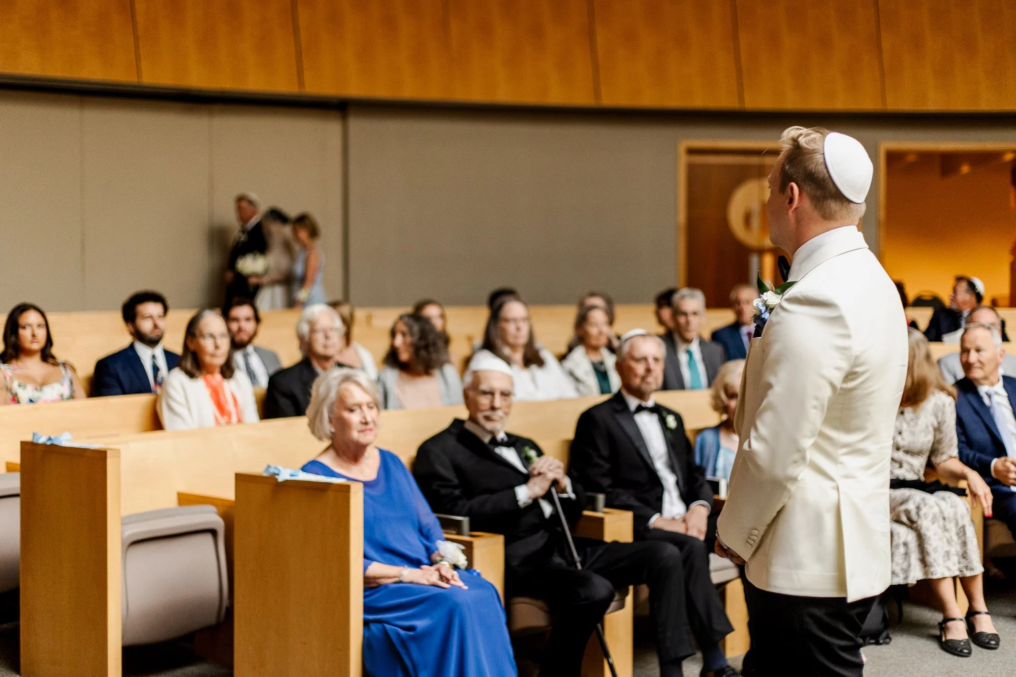 Owen watching Sarah come down the aisle during their Jewish wedding ceremony in Temple Shir Shalom sanctuary