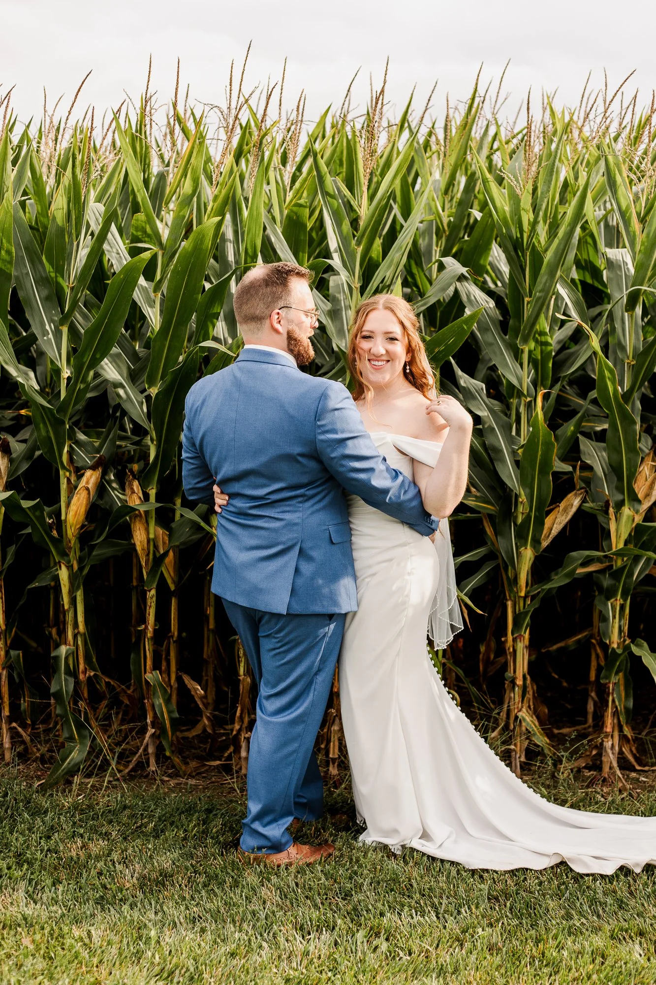 full length portrait of bride and groom happily standing and embracing in front of a corn field at bloom and bower in rising sun ohio