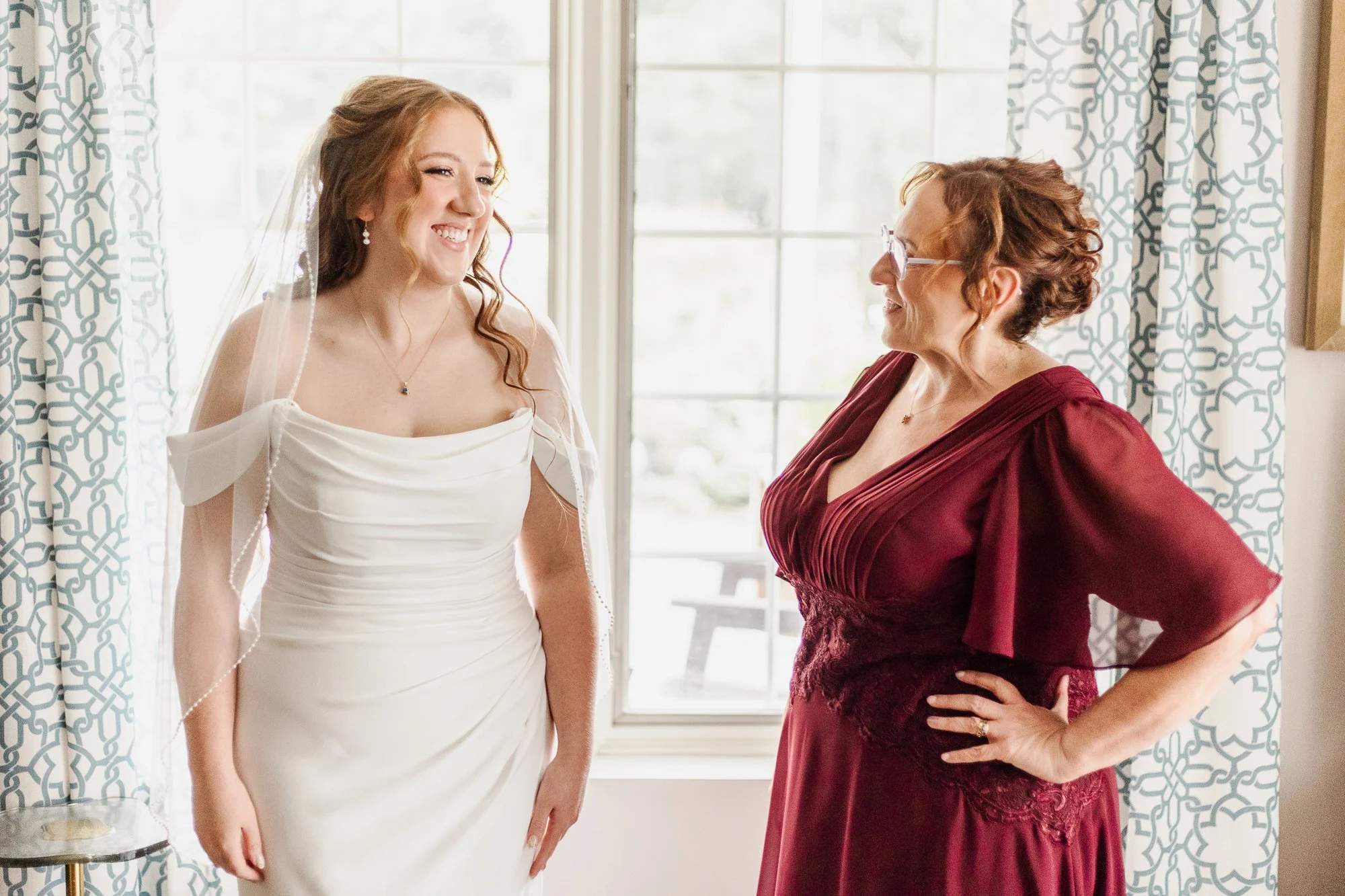 Half-body shot of Mom and bride laughing together after bride is fully dressed and ready for the ceremony