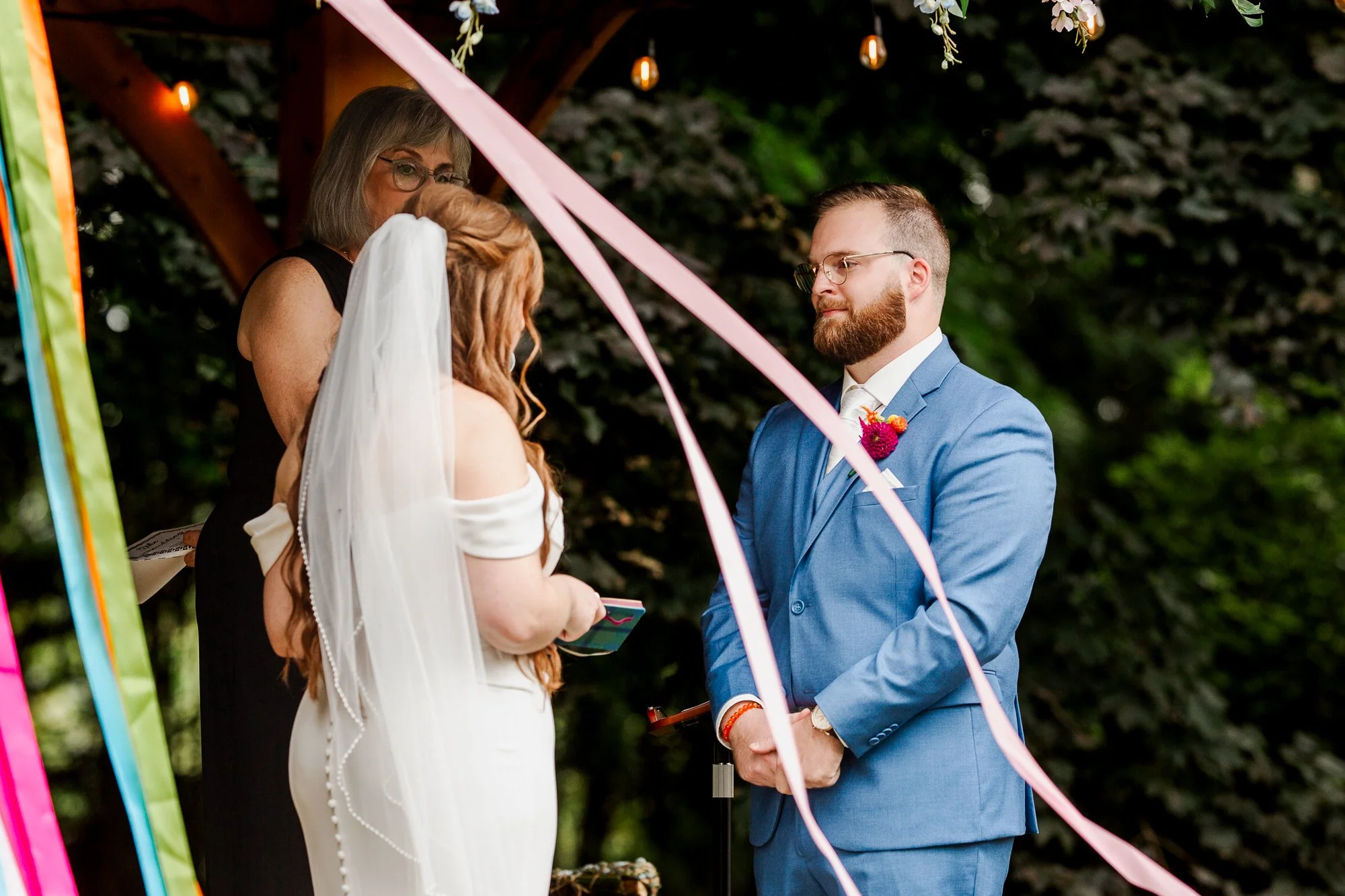 close up of bride and groom holding hands and facing each other at the alter during ceremony